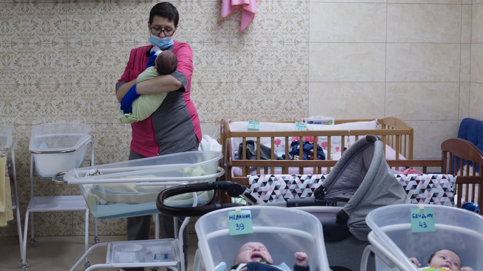 A woman cares for a surrogate-born baby in a makeshift basement shelter in Kyiv, Ukraine following after Russia's invasion.