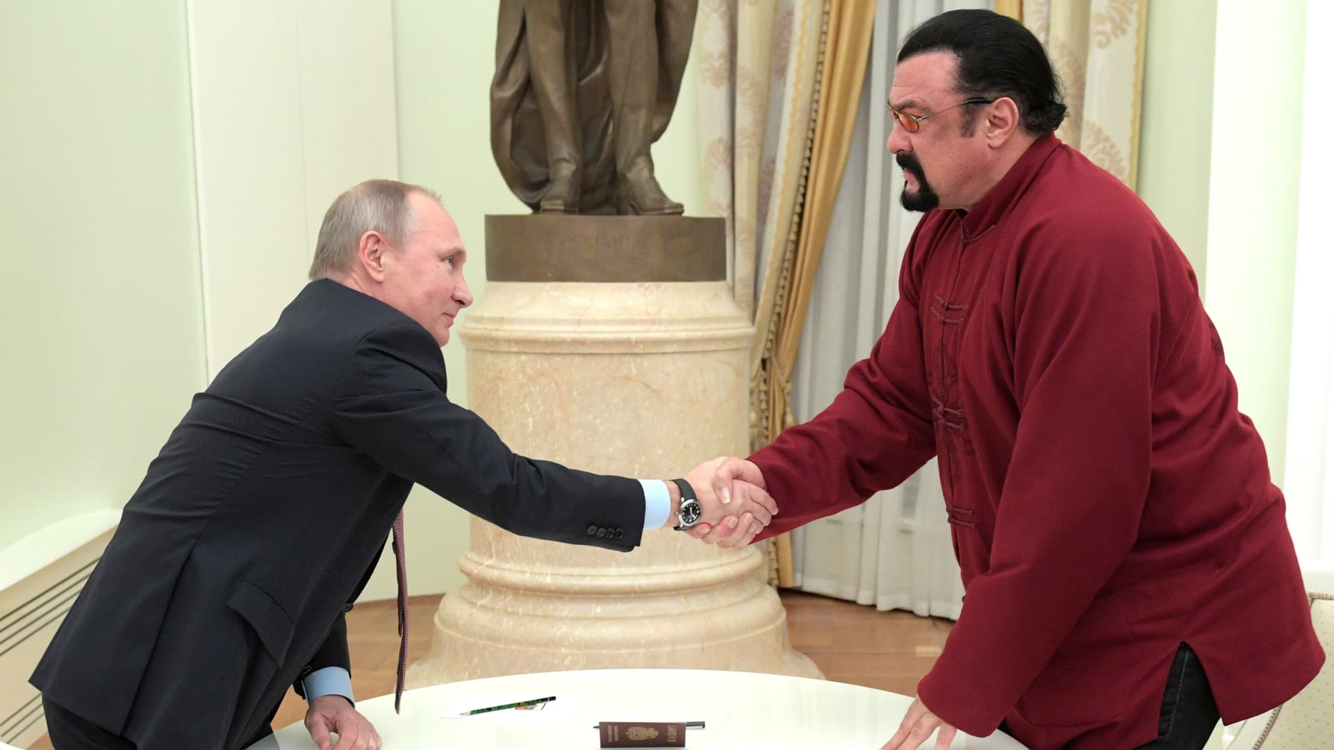 Russian President Vladimir Putin (L) shakes hands with US action hero actor Steven Seagal after presenting a Russian passport to him during a meeting at the Kremlin in Moscow on November 25, 2016.