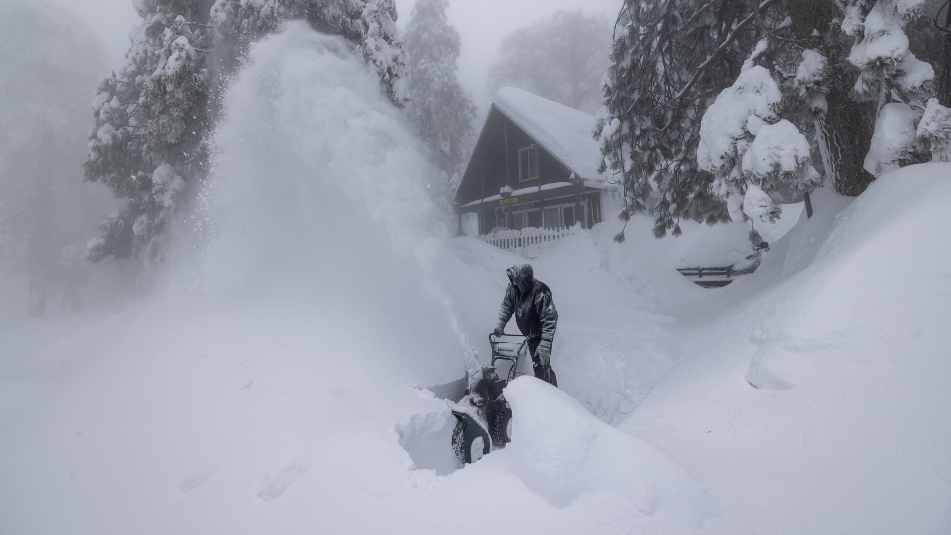 Robert Hallmark, who says that this is the worst snowstorm of his 31 years living here, clears snow at his home as residents throughout the San Bernardino Mountains continue to be trapped in their homes by snow on March 1, 2023 in Running Springs, California.