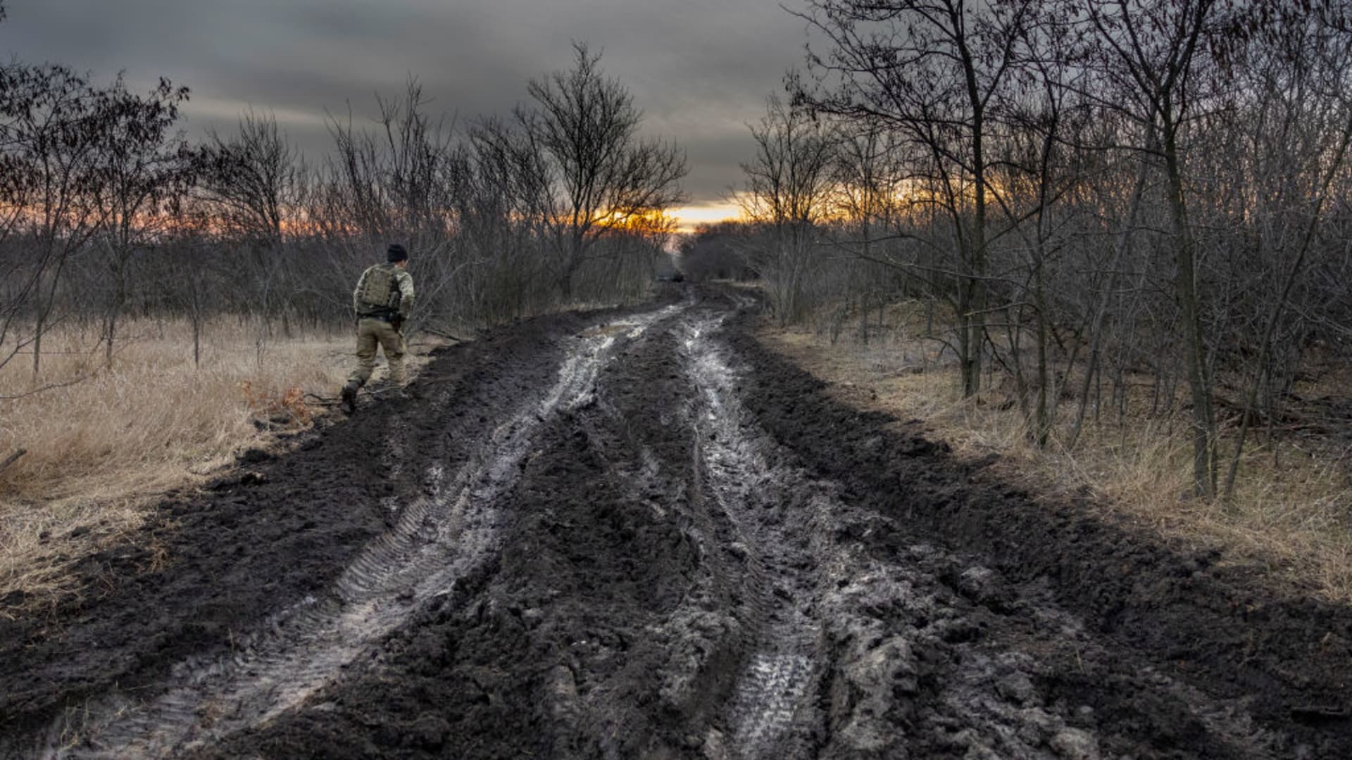 A soldier from a Ukrainian assault brigade walks along a muddy road used to transport and position British-made L118 105mm Howitzers, on March 4, 2023, near Bakhmut, Ukraine.