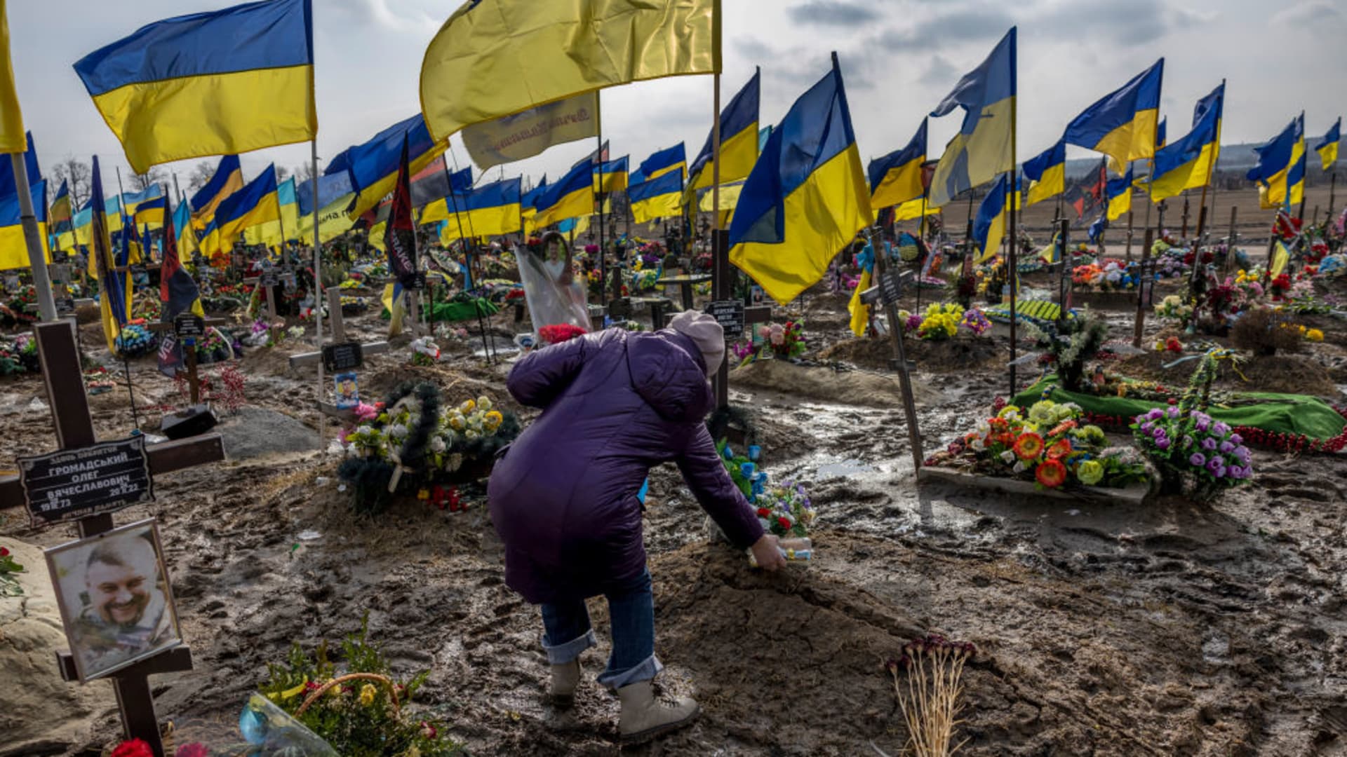 A woman places a container of food atop the grave of her son in the soldier's section of a cemetery on March 07, 2023 in Kharkiv, Ukraine. Last February, Russia's military invaded Ukraine from three sides and launched airstrikes across the country.