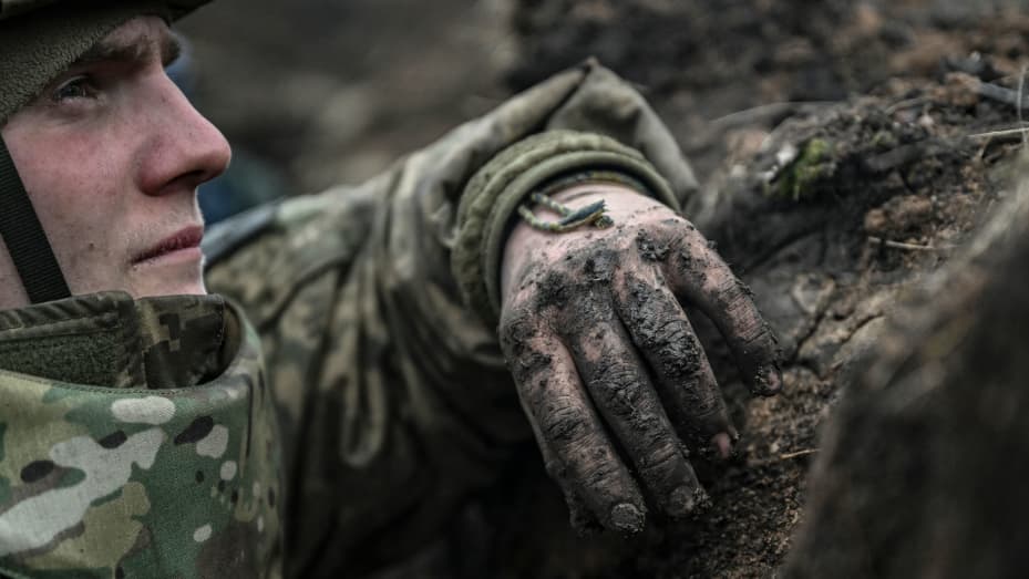 A Ukrainian serviceman takes cover in a trench during shelling next to a 105mm howitzer near the city of Bakhmut, on March 8, 2023, amid the Russian invasion of Ukraine.