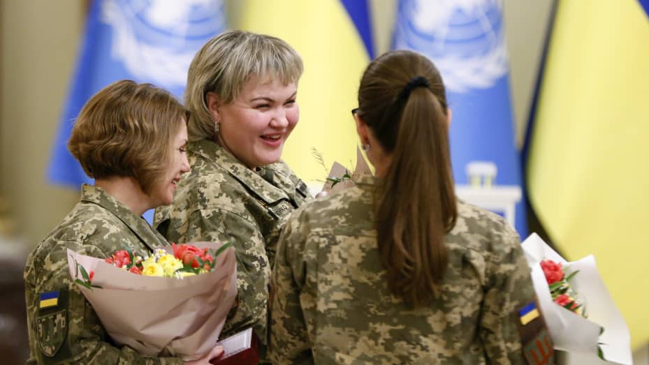 Ukrainian female soldiers stand with flowers and state awards awarded by the Ukrainian President during the International Women's Day celebration in Kyiv on March 08, 2023.