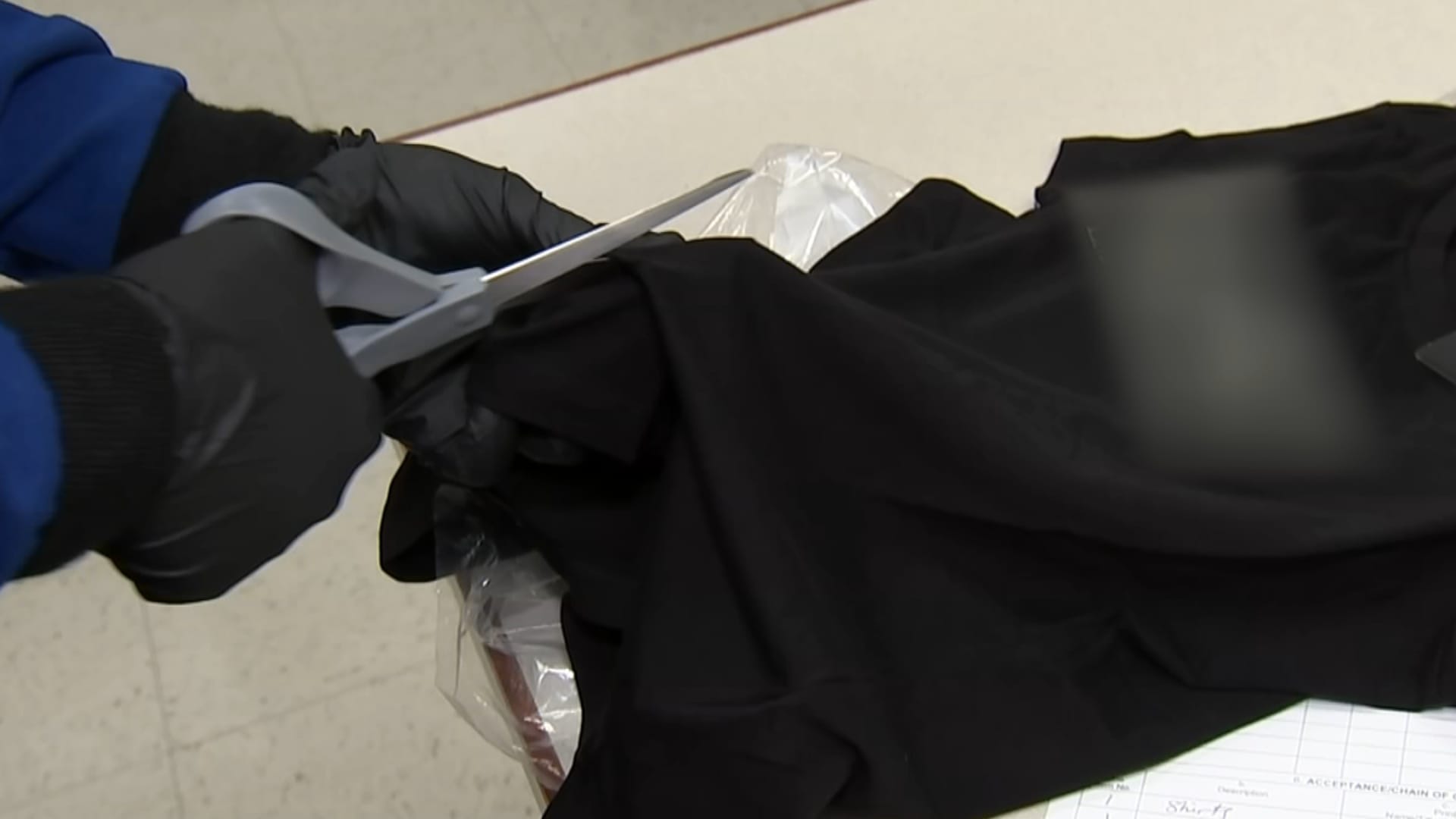 A scientist at a U.S. Customs & Border Protection lab in Newark, New Jersey, cuts a T-shirt from a well-known designer fashion label with scissors for testing.