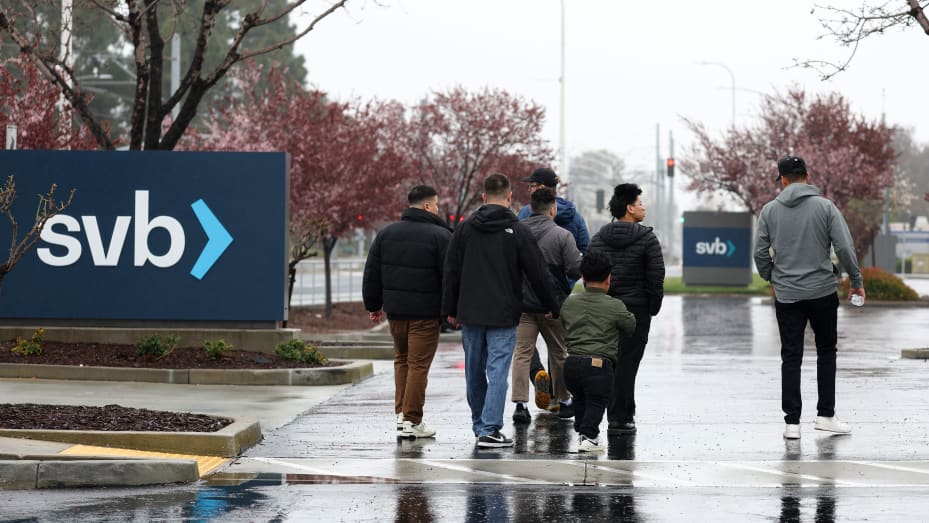 SANTA CLARA, CALIFORNIA - MARCH 10: People walk through the parking lot at the Silicon Valley Bank (SVB) headquarters on March 10, 2023 in Santa Clara, California. Silicon Valley Bank was shut down on Friday morning by California regulators and was put in control of the U.S. Federal Deposit Insurance Corporation. Prior to being shut down by regulators, shares of SVB were halted Friday morning after falling more than 60% in premarket trading following a 60% declined on Thursday when the bank sold off a portf