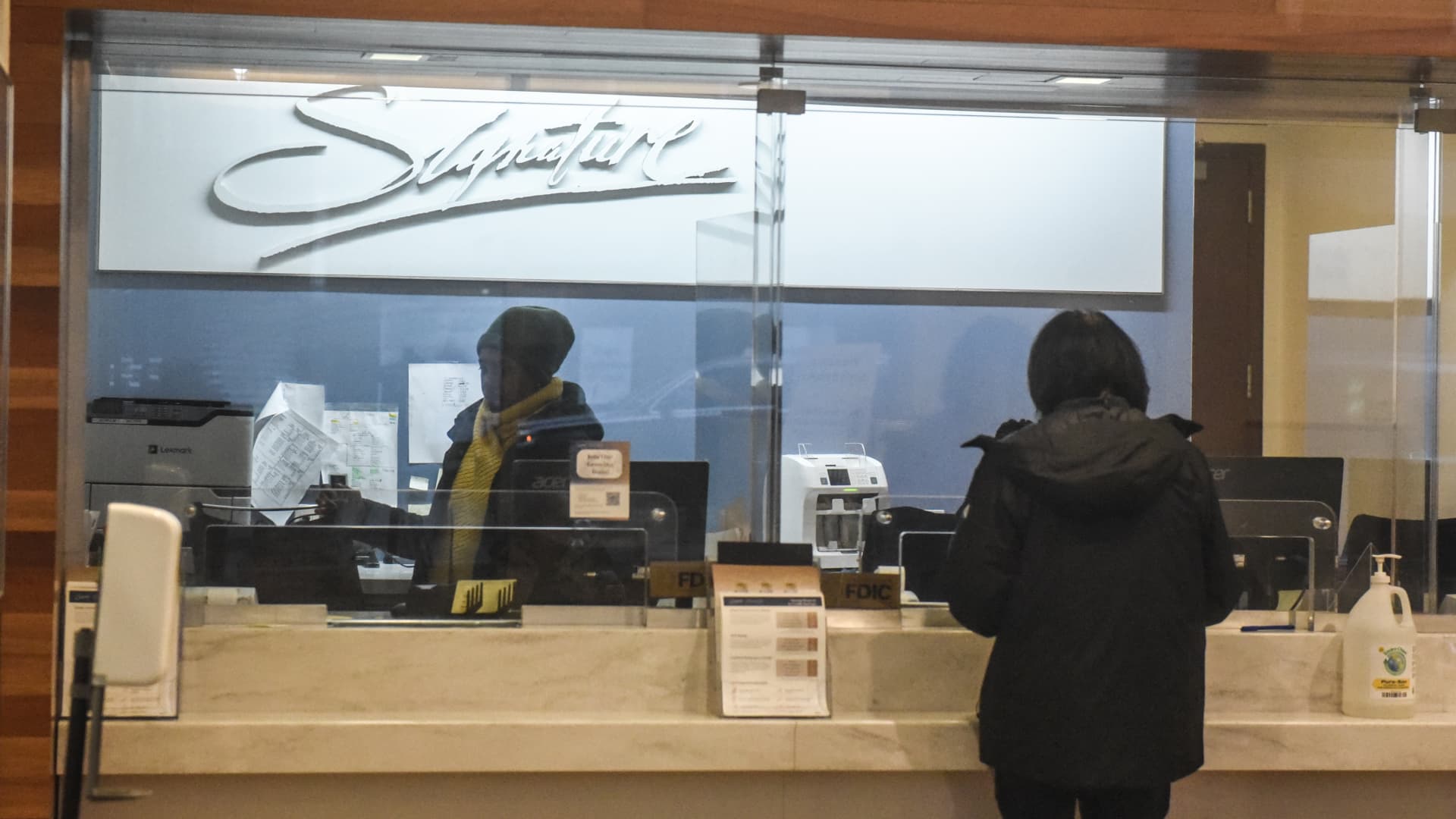 A worker assists a customer at a Signature Bank branch in New York, US, on Monday, March 13, 2023.