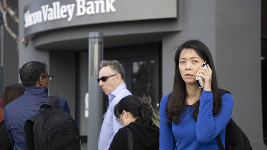 People queue up outside the headquarters of Silicon Valley Bank to withdraw their funds on March 13, 2023 in Santa Clara, California.