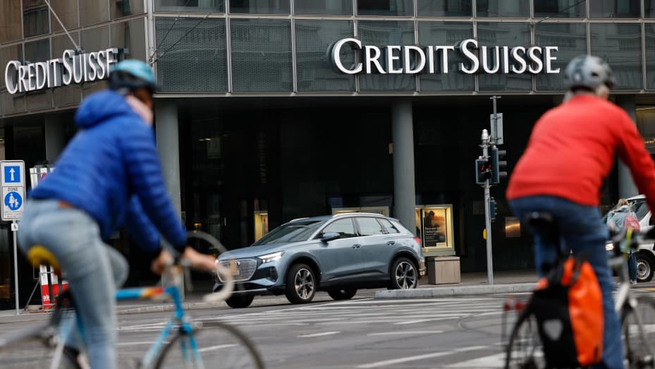 Commuters cycle past a Credit Suisse Group AG bank branch in Basel, Switzerland, on Tuesday, Oct. 25, 2022. Credit Suisse will present its third quarter earnings and strategy review on Oct. 27.