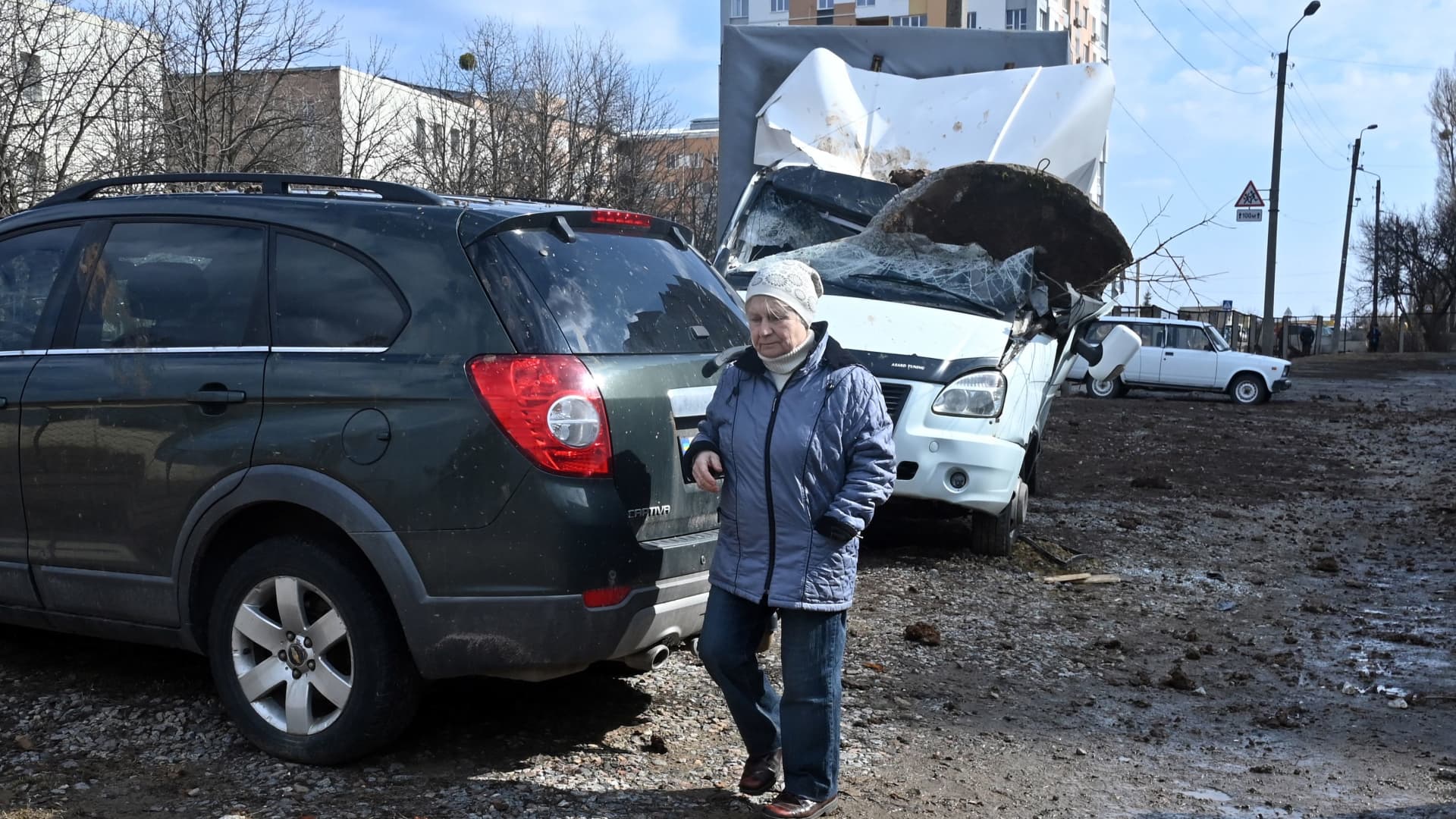 A woman walks past a damages vehicle after a Russian missile strike in the city of Kharkiv on March 15, 2023.