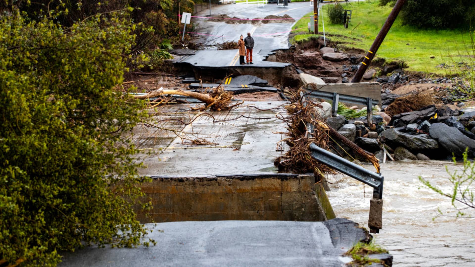 Residents checkout the damage after the fast moving and swollen Tulare River crumbled parts of Globe Drive on March 14, 2023 in Springville, California.
