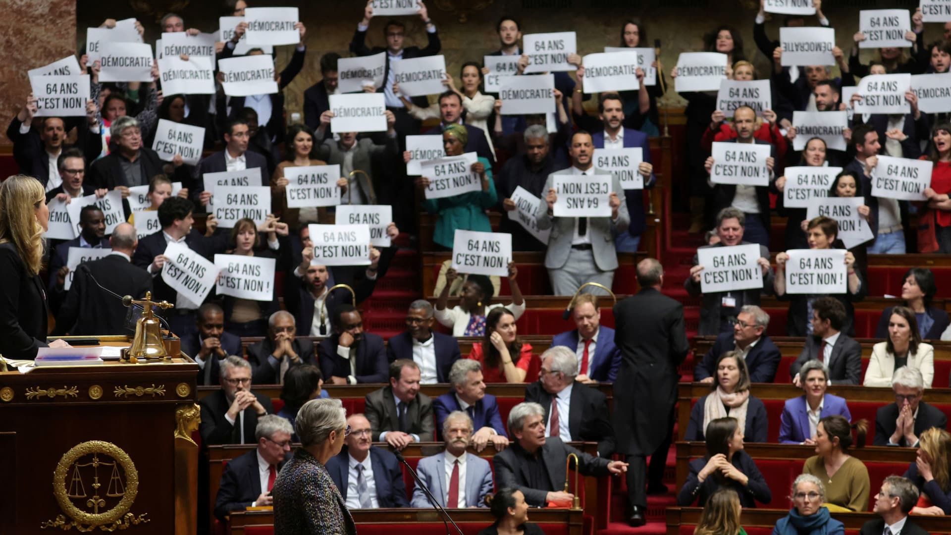 Members of parliament of the left hold placards and sing the Marseillaise, French national anthem,as French Prime Minister Elisabeth Borne arrives to deliver a speech on pensions reform bill at the National Assembly in Paris, France, March 16, 2023. 