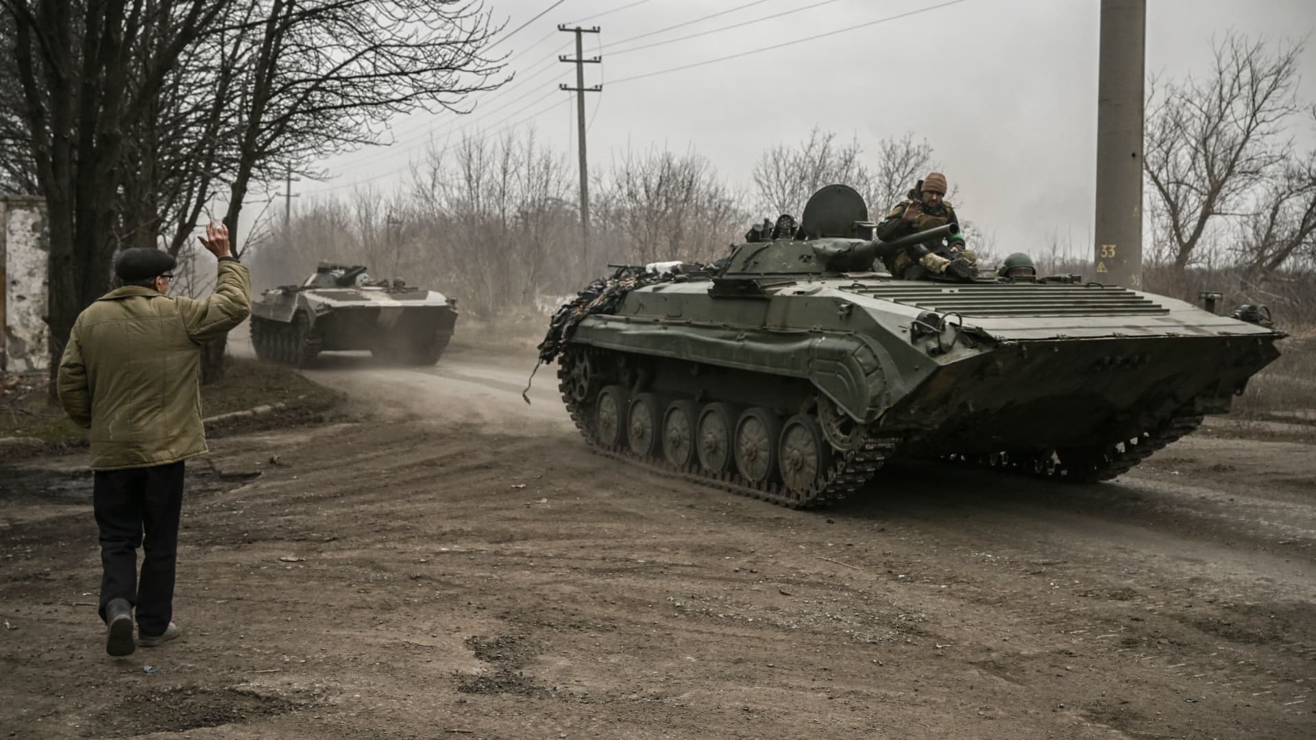 A local resident waves at a Ukrainian infantry fighting vehicle BMP-1 on their way to the frontline, near Bakhmut, eastern Ukraine, on March 17, 2023, amid the Russian invasion of Ukraine.