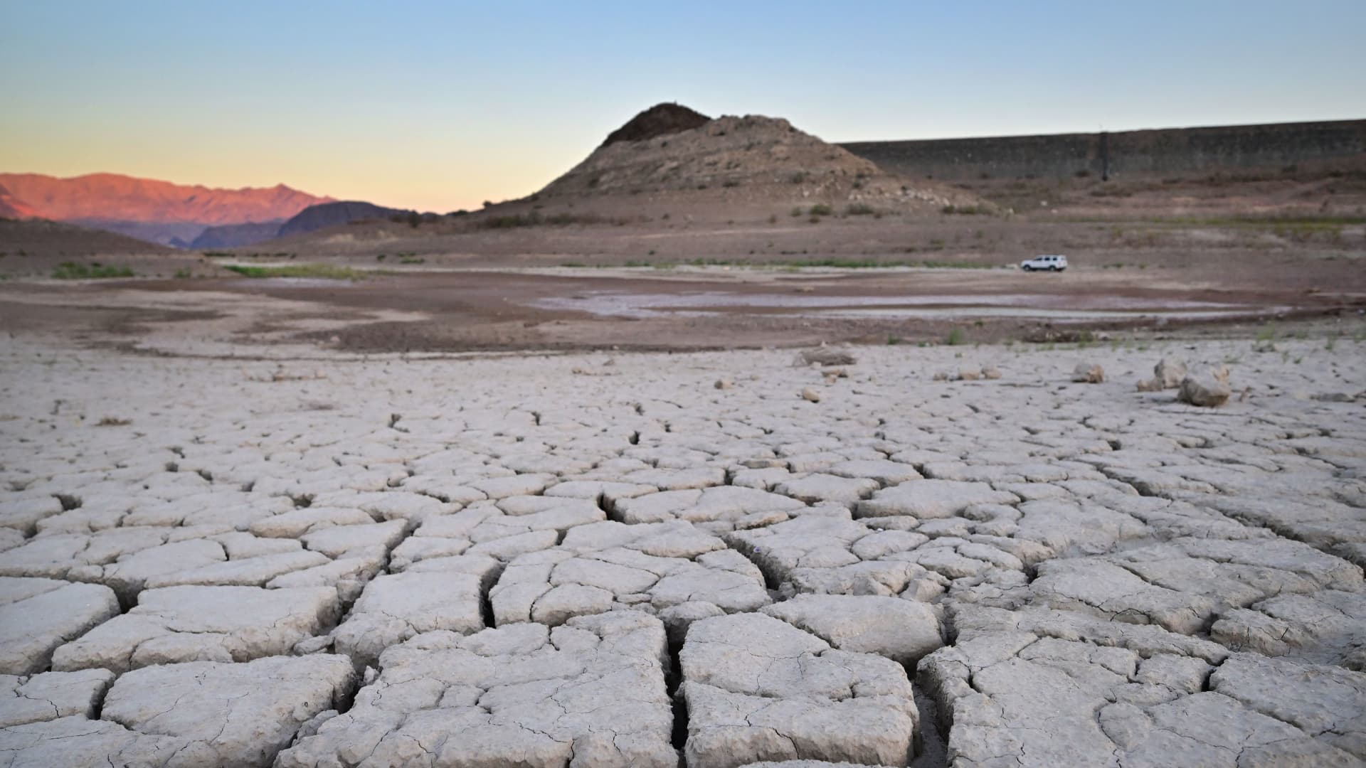 A vehicle drives past a dry, cracked lake bed on its way to Boulder Harbour in drought-stricken Lake Mead on September 15, 2022 in Boulder City, Nevada.