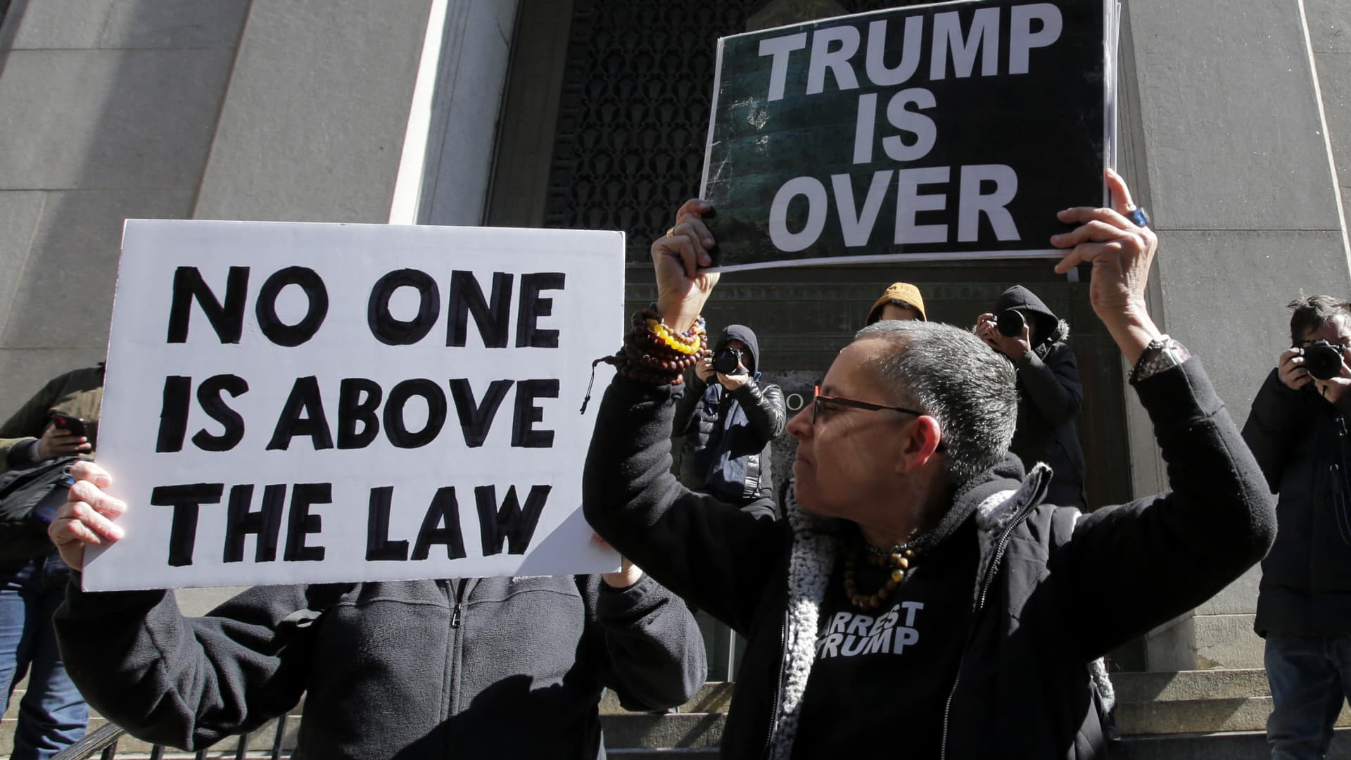 Anti-Trump demonstrators hold placards outside the Manhattan District Attorney's office in New York City on March 20, 2023.