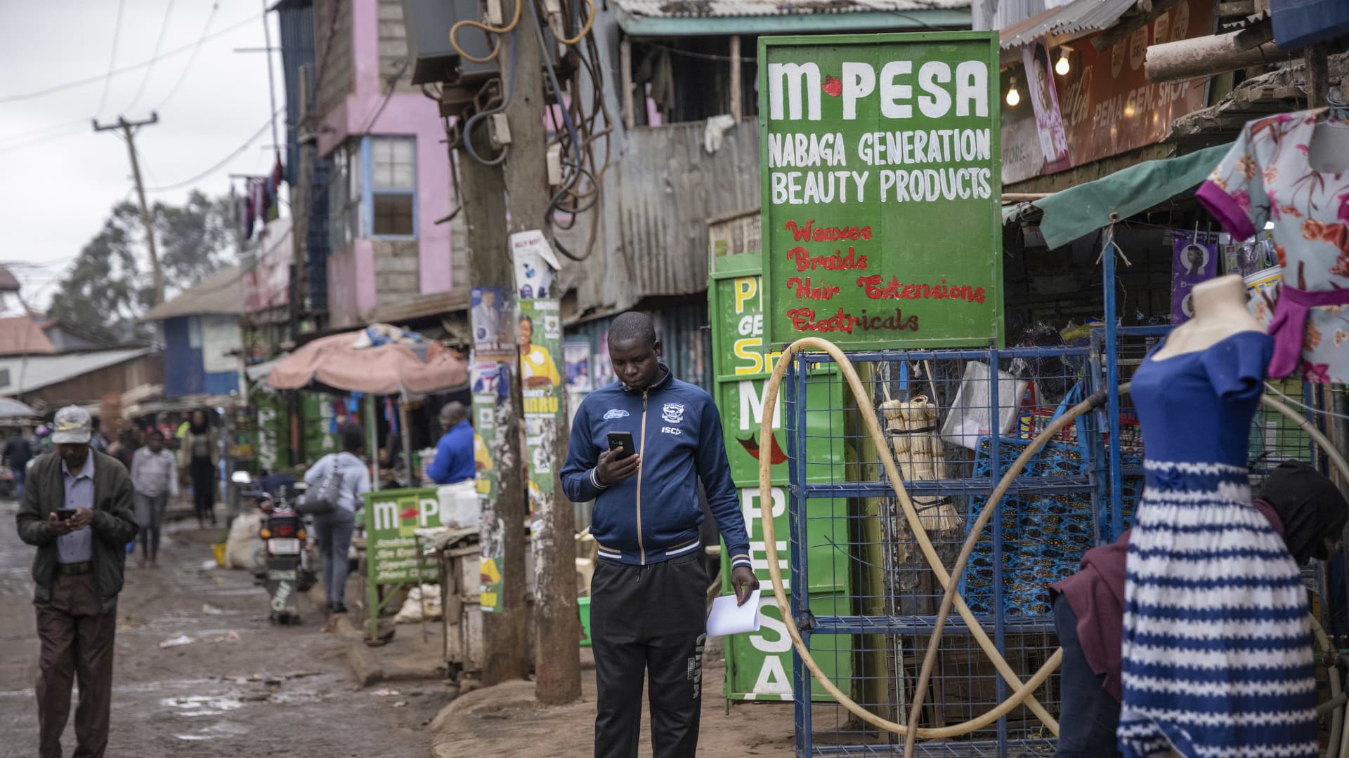 A resident checks his phone outside a mobile money kiosk in the Kibera district of Nairobi, Kenya, on Monday, Aug. 1, 2022.