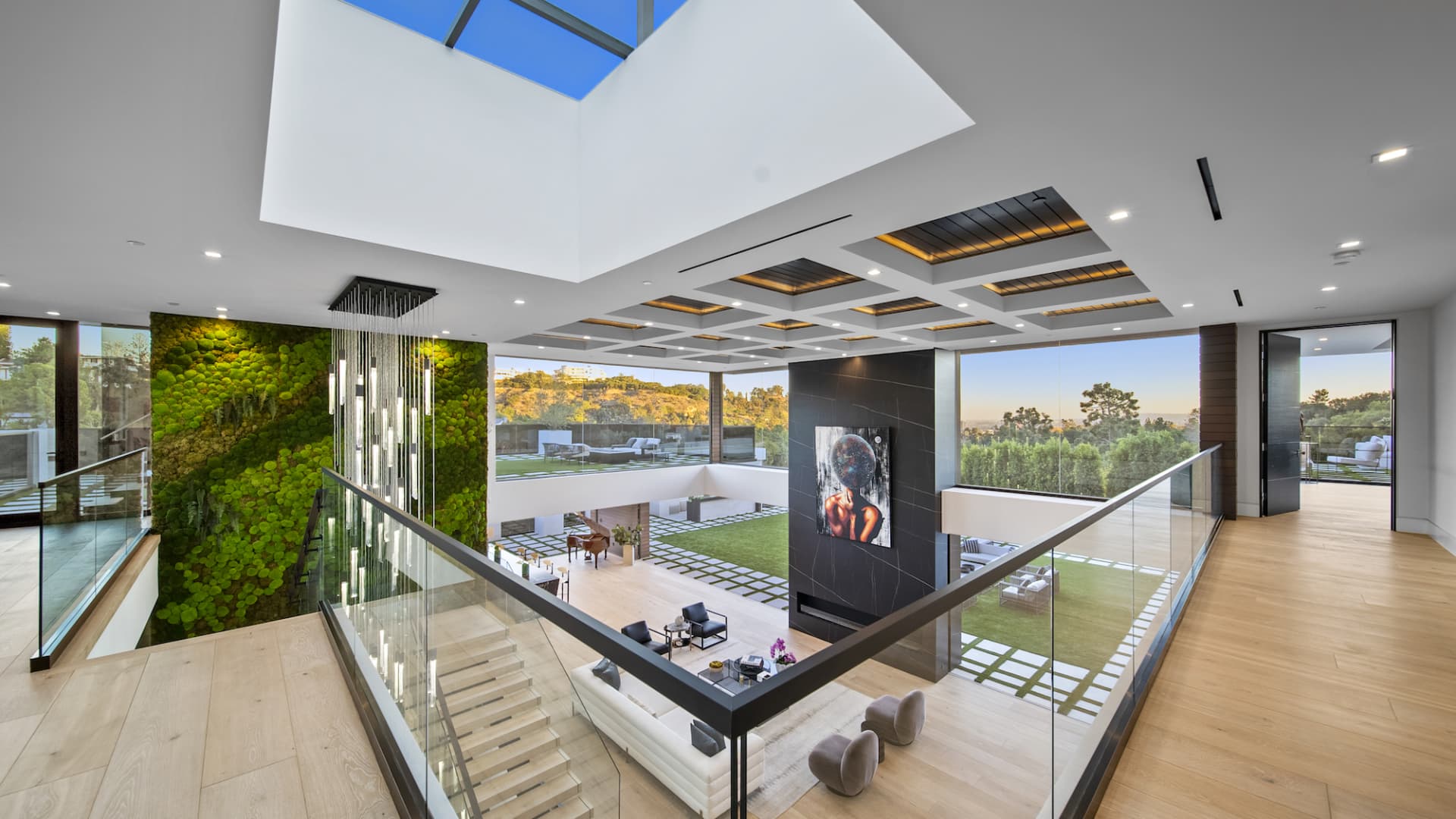 The grand living area opens to the outdoors with 22 foot ceilings, a 10-ft long fireplace, and a giant wall covered in living green moss that extends across three levels of the home.