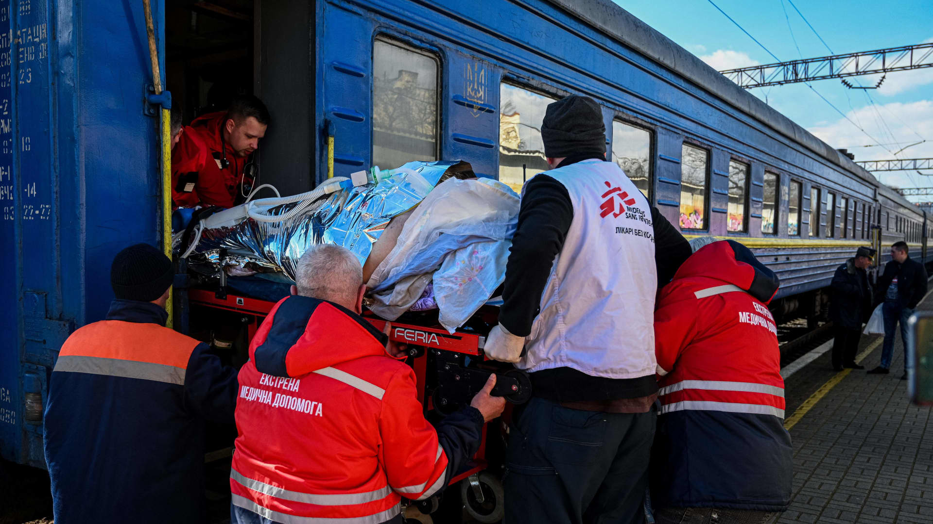 Medical workers, helped by a member of Doctors Without Borders (MSF) NGO, unload a stretcher with a wounded civilian patient upon his arrival from eastern Ukraine to be treated in the western Ukrainian city of Lviv on March 17, 2023, amid the Russian invasion of Ukraine.