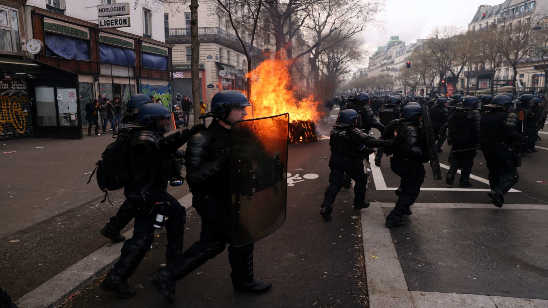 French gendarmes react near burning garbage bins amid clashes with protesters during a demonstration as part of the ninth day of nationwide strikes and protests against French government's pension reform, in Paris, France, March 23, 2023. 