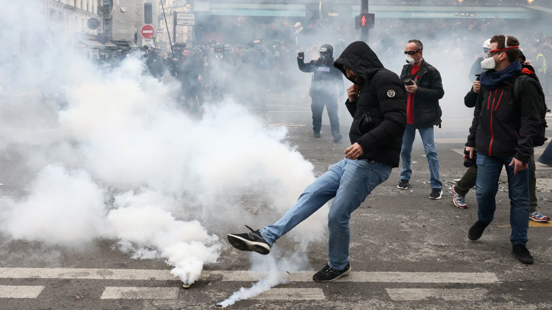 Protesters throw tear gas canisters back amid clashes during a demonstration as part of the ninth day of nationwide strikes and protests against French government's pension reform, in Paris, France, March 23, 2023. 