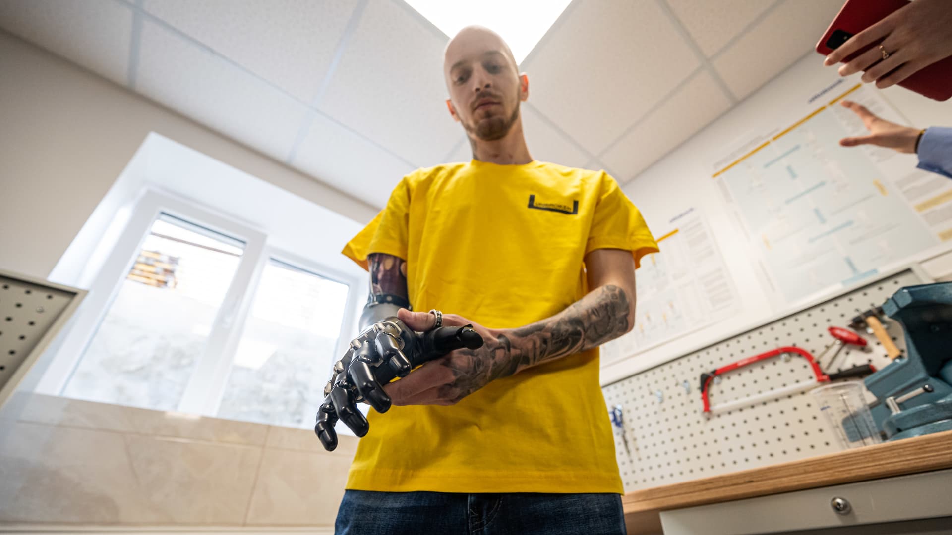 A man with a bionic prosthetic hand shows how a prosthesis functions, holding a hammer in his prosthetic hand on March 23, 2023 in Lviv, Ukraine. 