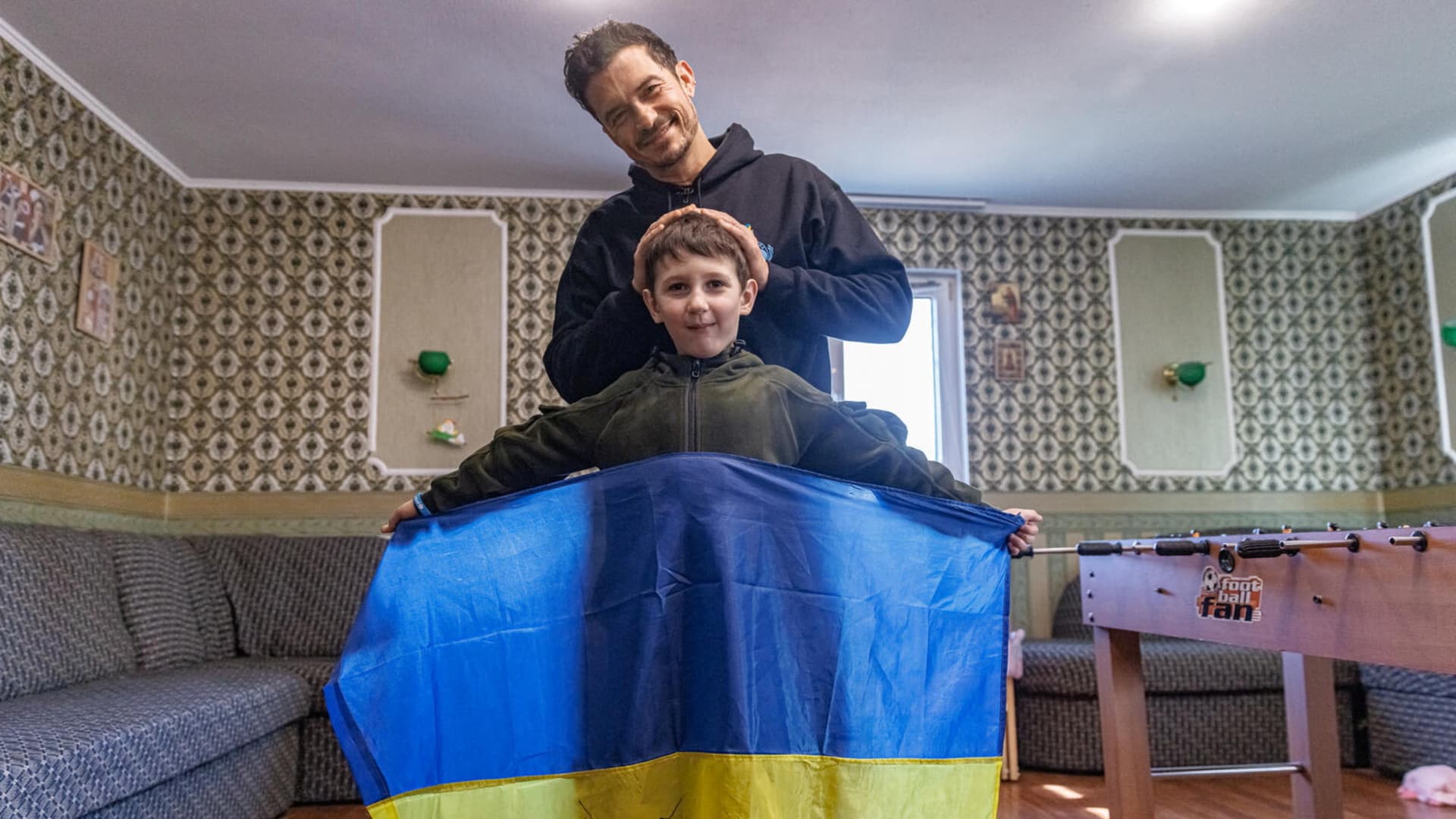 Actor and UNICEF Goodwill Ambassador Orlando Bloom poses with Yehor, 8, holding a Ukrainian flag signed by Orlando, in Demydiv, Ukraine, March 26, 2023 in this handout image. UNICEF/Skyba/Handout via REUTERS THIS IMAGE HAS BEEN SUPPLIED BY A THIRD PARTY. MANDATORY CREDIT. NO RESALES. NO ARCHIVES