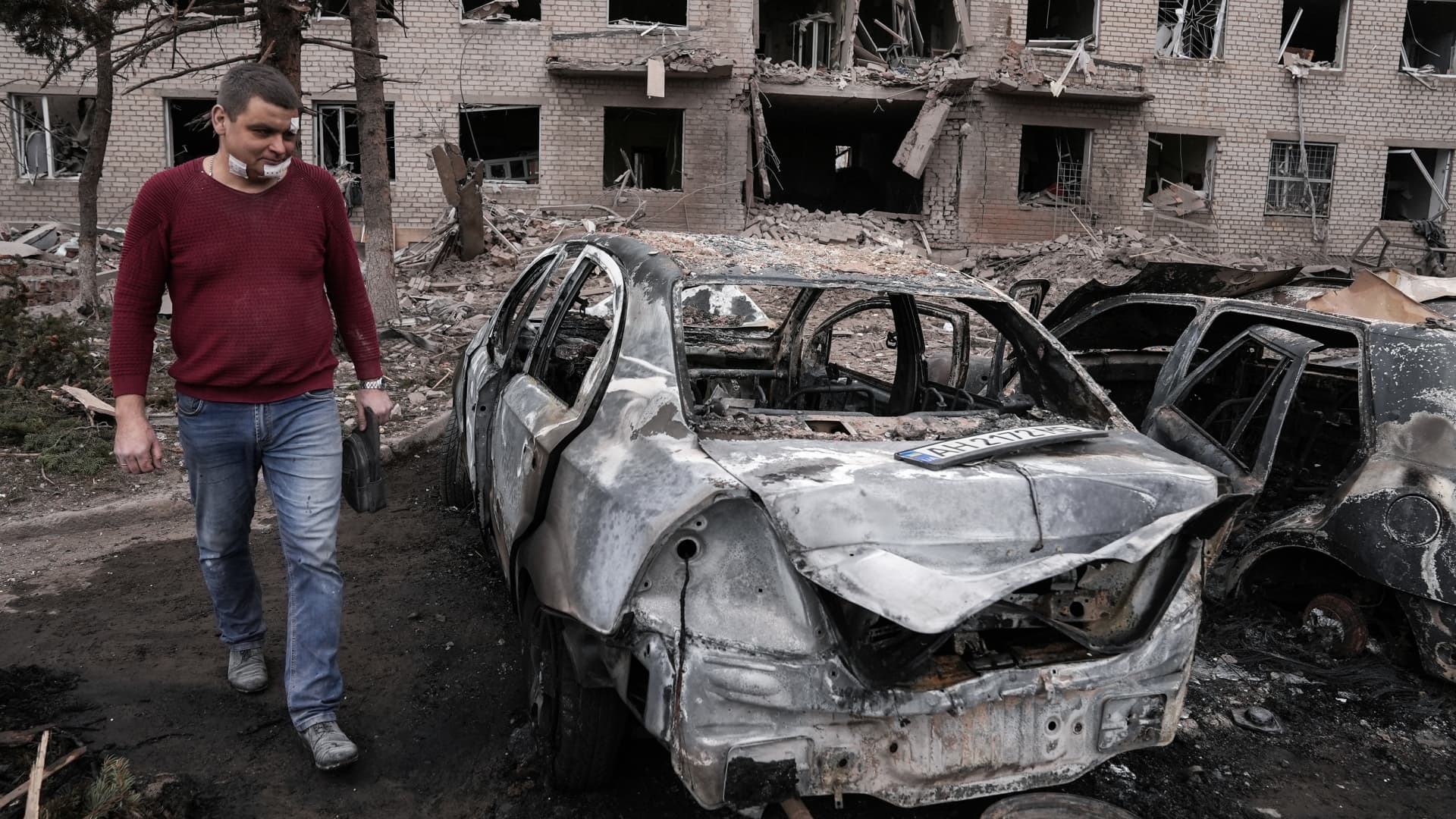 EDITORS NOTE: Image contains graphic content: A wounded man walks near burnt cars in front of a destroyed building in the city centre on March 27, 2023 in Sloviansk, Ukraine. 