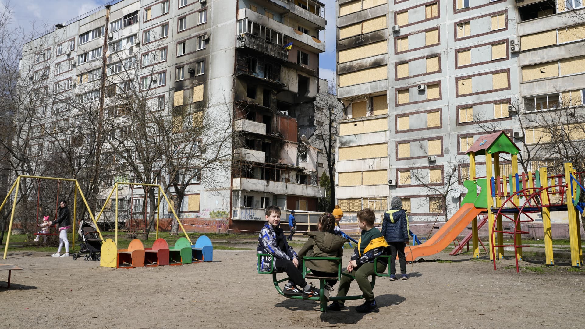 Children play in a playground in front of missile-damaged buildings ahead of a visit by Ukraine's President Volodymyr Zelenskyy Zaporizhzhia, Ukraine, Monday March 27, 2023. 
