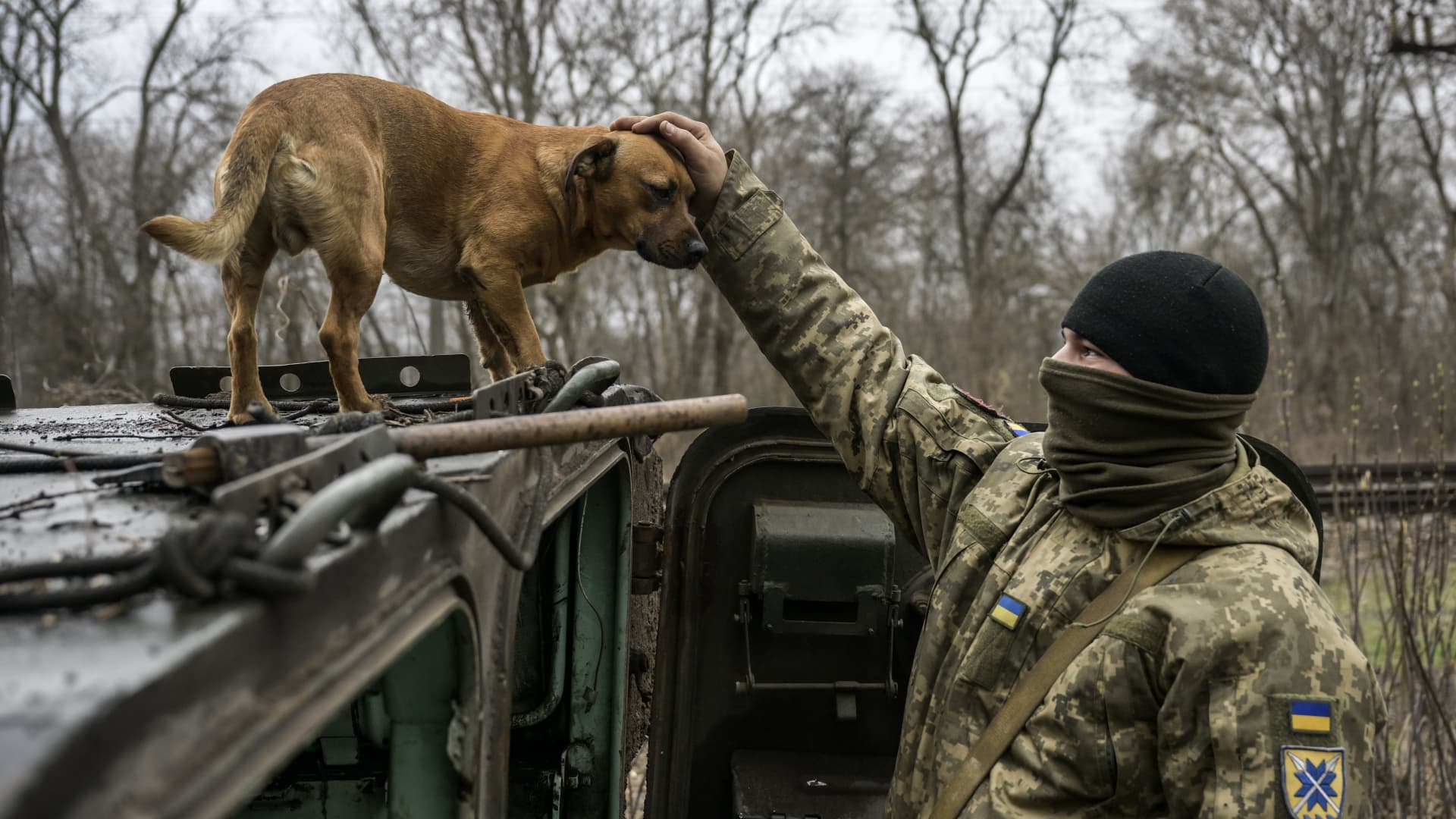 A Ukrainian soldier with a stray dog next to an armored vehicle in Donetsk Oblast, Ukraine, on March 20, 2023.