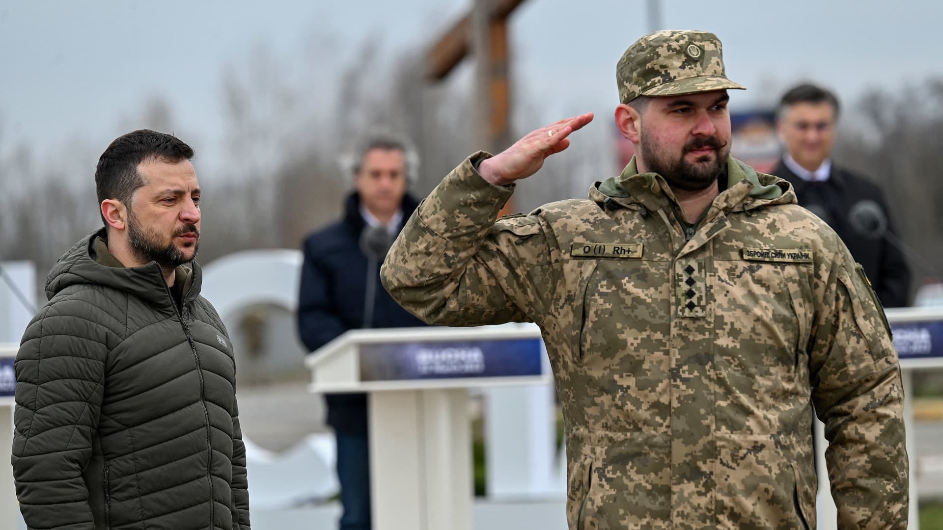 A Ukrainian serviceman salutes as he receives an award from Ukraine's President Volodymyr Zelensky (L), as part of a ceremony marking the first anniversary of the retreat of Russian troops from the Ukrainian town of Bucha, in Bucha, near Kyiv, on March 31, 2023.
