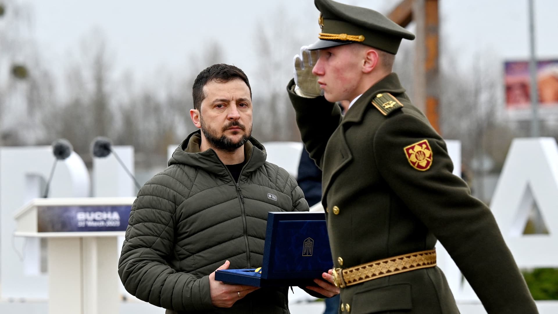 Ukraine's President Volodymyr Zelensky (C) holds an award as he attends a ceremony marking the first anniversary of the retreat of Russian troops from the Ukrainian town of Bucha, in Bucha, near Kyiv, on March 31, 2023. 