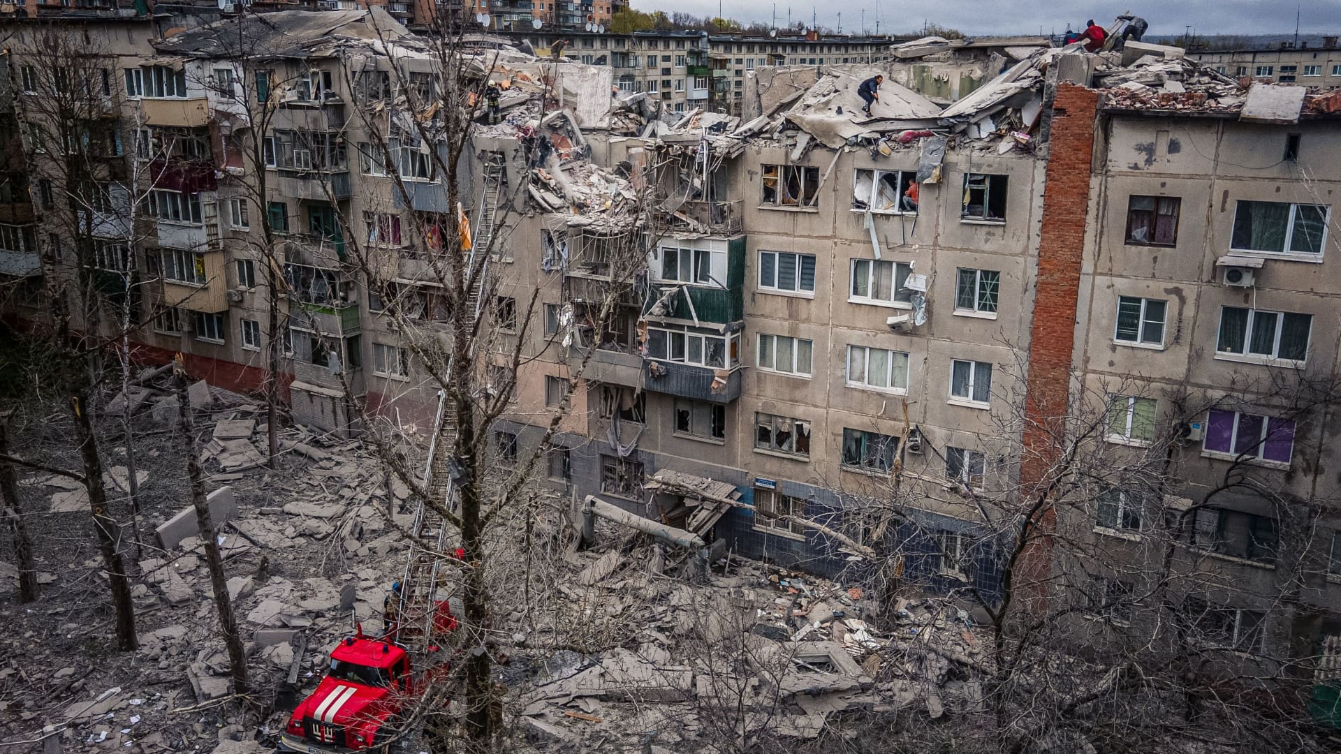 This aerial view shows rescuers on top of a partially destroyed residential building, after a shelling in Sloviansk, on April 14, 2023, amid Russia's military invasion on Ukraine. 
