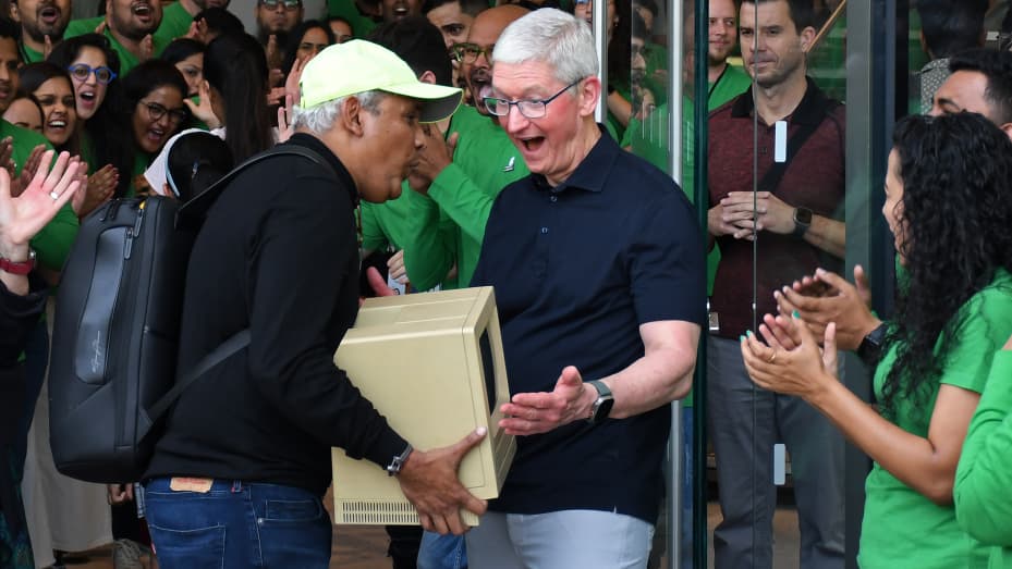 Tim Cook, Apple's Chief Executive Officer (CEO) reacts as a man shows him Apple's Macintosh outside the Apple store at Jio World Drive mall, Mumbai, India on April 18, 2023.