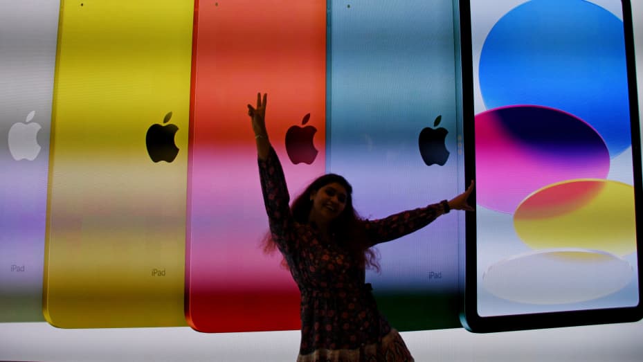 A woman poses for a photo near the screen displaying Apple's tablets inside the store after the launch at Jio World Drive mall, Mumbai, India, April 18, 2023.