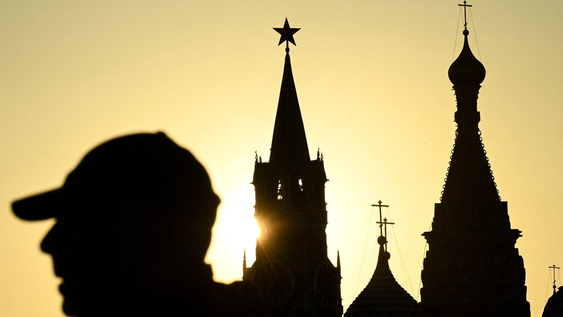 A man walks in Zaryadye park in front of the Kremlin's Spasskaya tower and St Basil's cathedral during the sunset in downtown Moscow on April 19, 2022. (Photo by Kirill KUDRYAVTSEV / AFP) (Photo by KIRILL KUDRYAVTSEV/AFP via Getty Images)