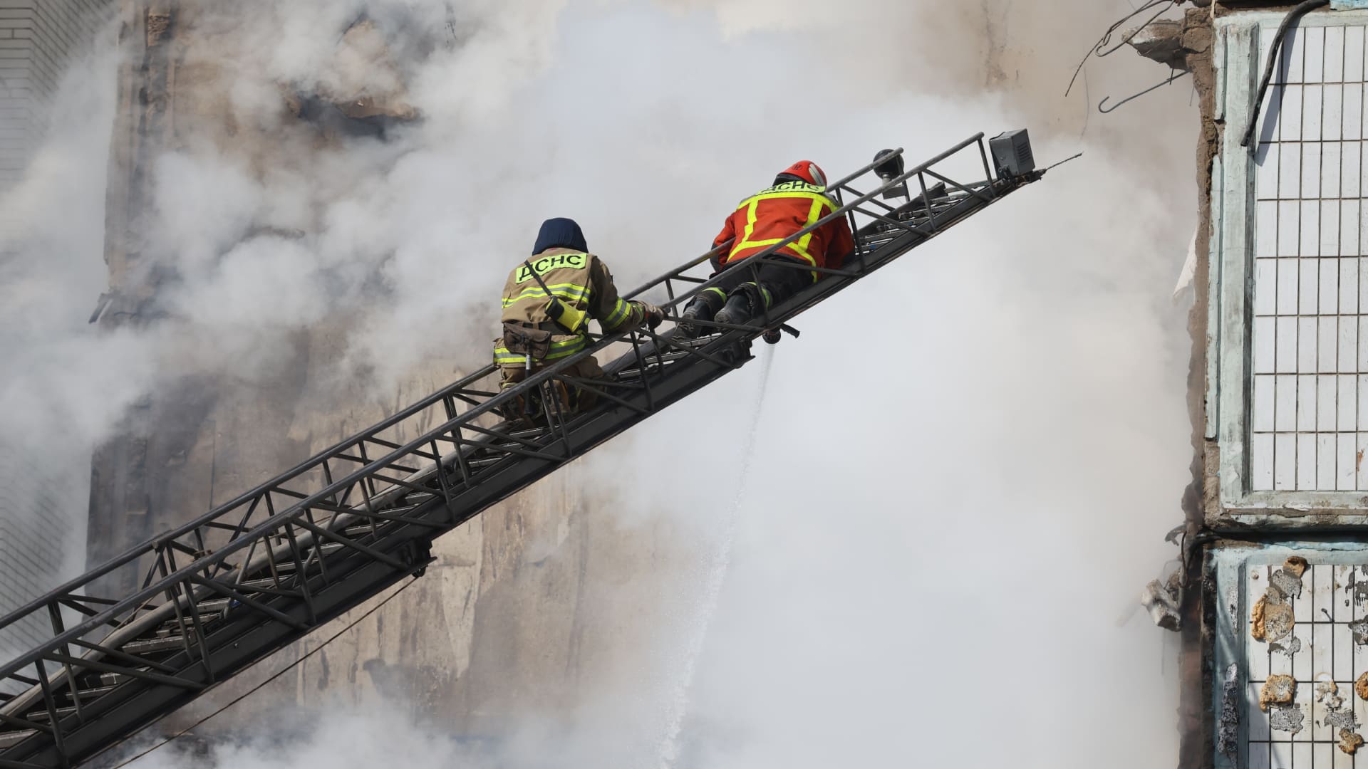 Firefighters on ladder extinguish a fire while their colleagues conduct search and rescue operation on April 28, 2023 in Uman, Ukraine.
