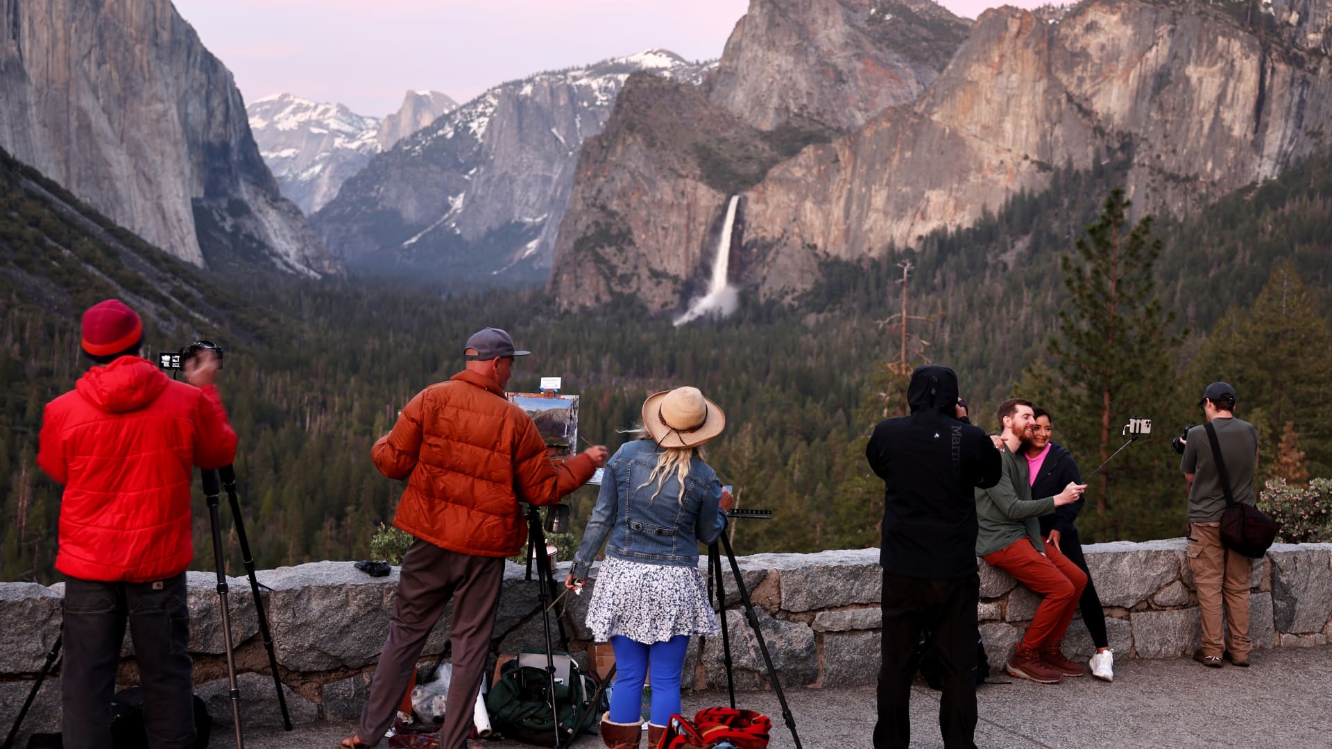 People paint and take photos as water flows forcefully down Bridalveil Fall in Yosemite Valley, as warming temperatures have increased snowpack runoff, on April 27, 2023 in Yosemite National Park, California. 
