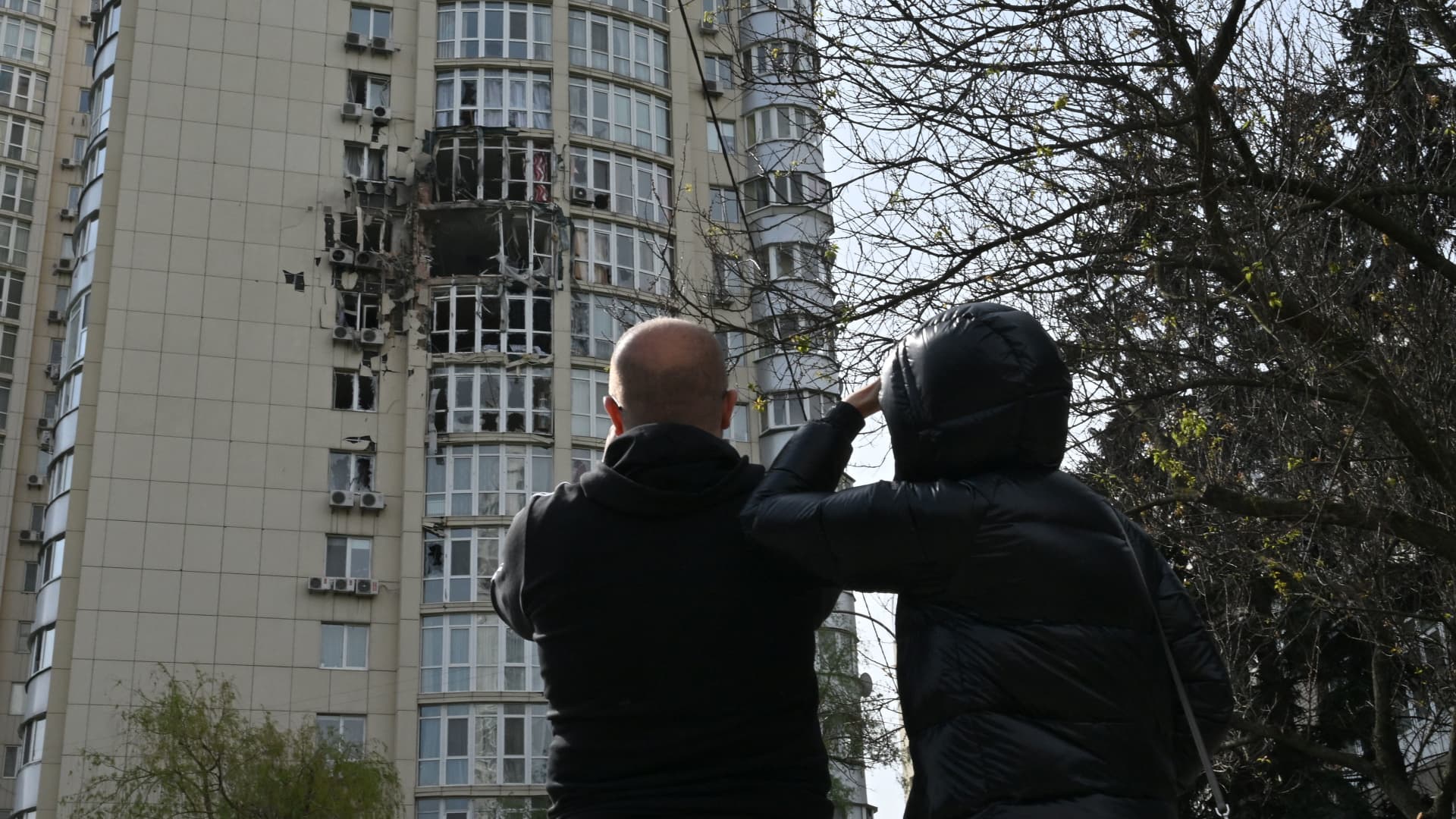 People look at a high-rise residential building damaged by remains of a shot down Russian drone in Kyiv on May 8, 2023, amid the Russian invasion of Ukraine. 