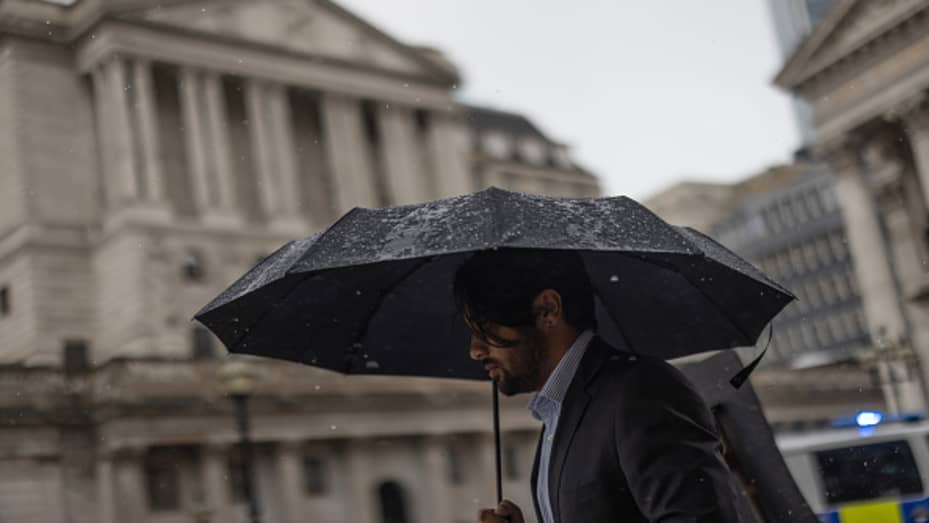 A member of the public walks through heavy rain near the Bank of England in May 2023.