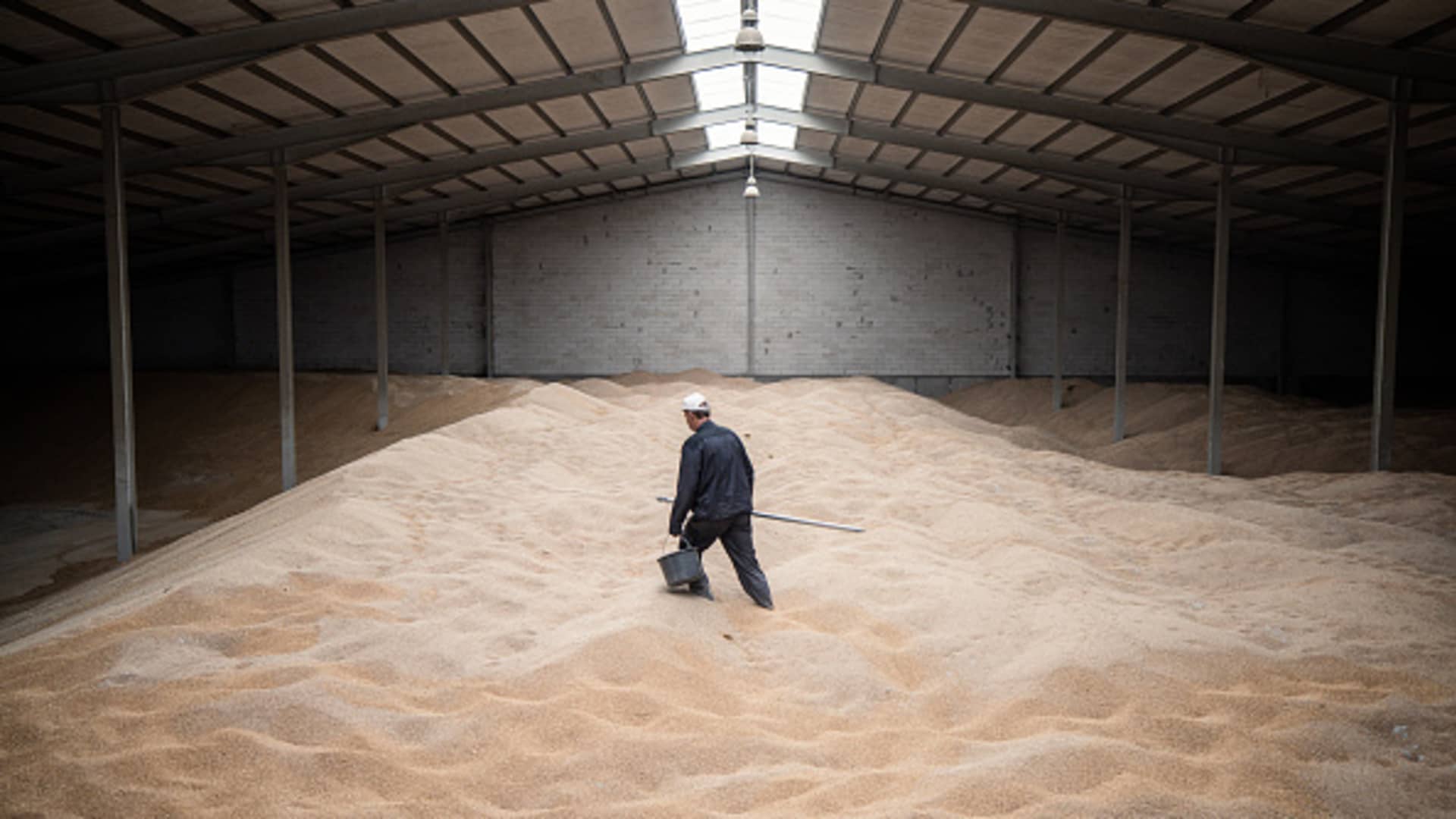 A worker walks on top of a pile of wheat grain in a storage granary at Aranka Malom kft mill in Bicske, Hungary on Tuesday, May 16, 2023. The Black Sea deal has allowed Ukraine to ship more than 30 million tons of produce from three major ports, helping to bring down global food prices down after they spiked following Russia's invasion. 