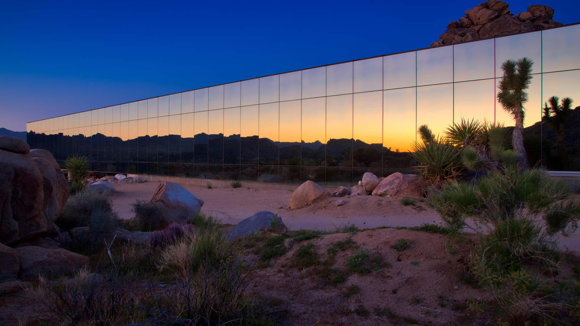 The Invisible House's mirrored facade reflecting the desert sunrise.