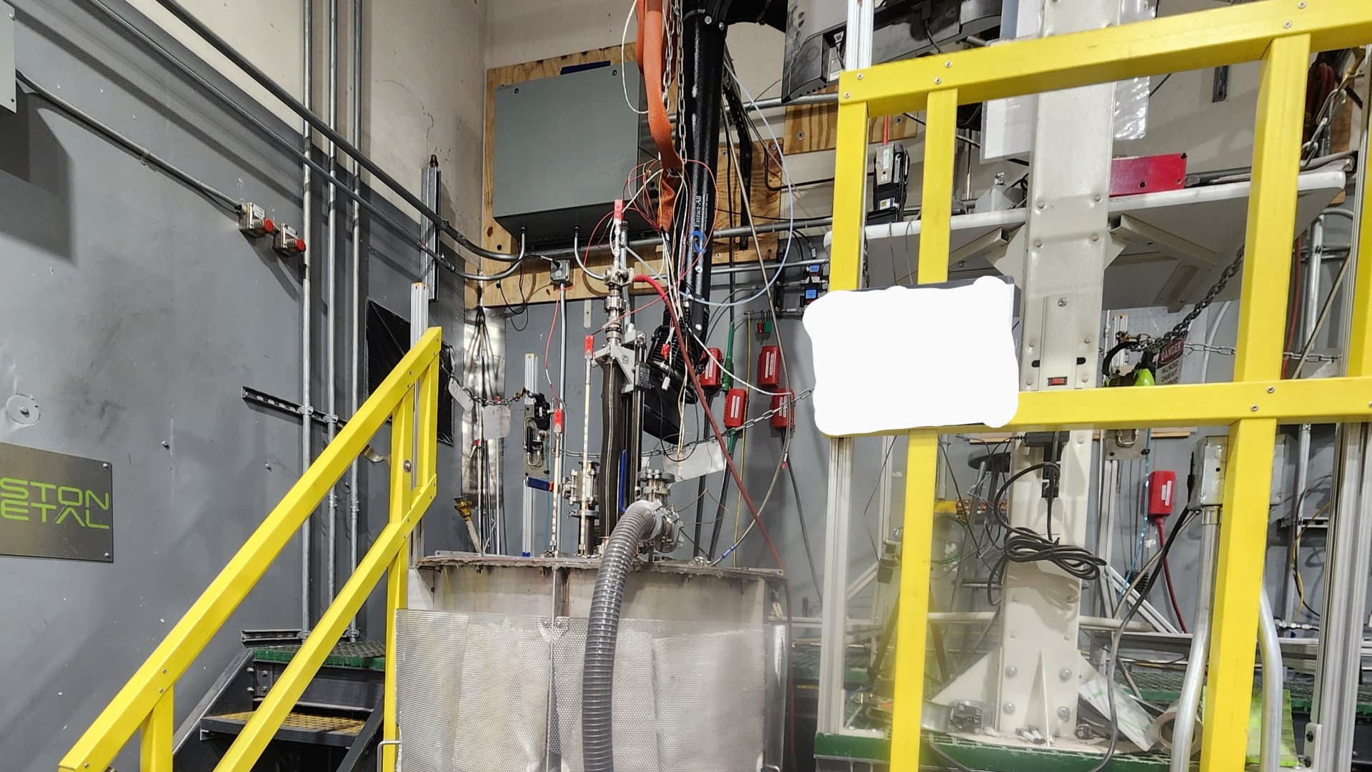 This is a mid-size electrolysis device, between the lab scale bench and the full-scale cell. This can run for weeks at a time and gathers performance data for the anode. (The text on the white board has been covered to protect the intellectual property of Boston Metal.) 