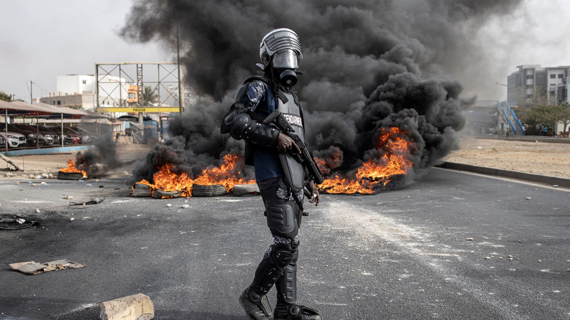 DAKAR, Senegal - May 29, 2023: A Senegalese gendarme stands near a smoke billowing from burning tyres during a protest over the arrest of opposition leader Ousmane Sonko, ahead of the final verdict in his rape trial.