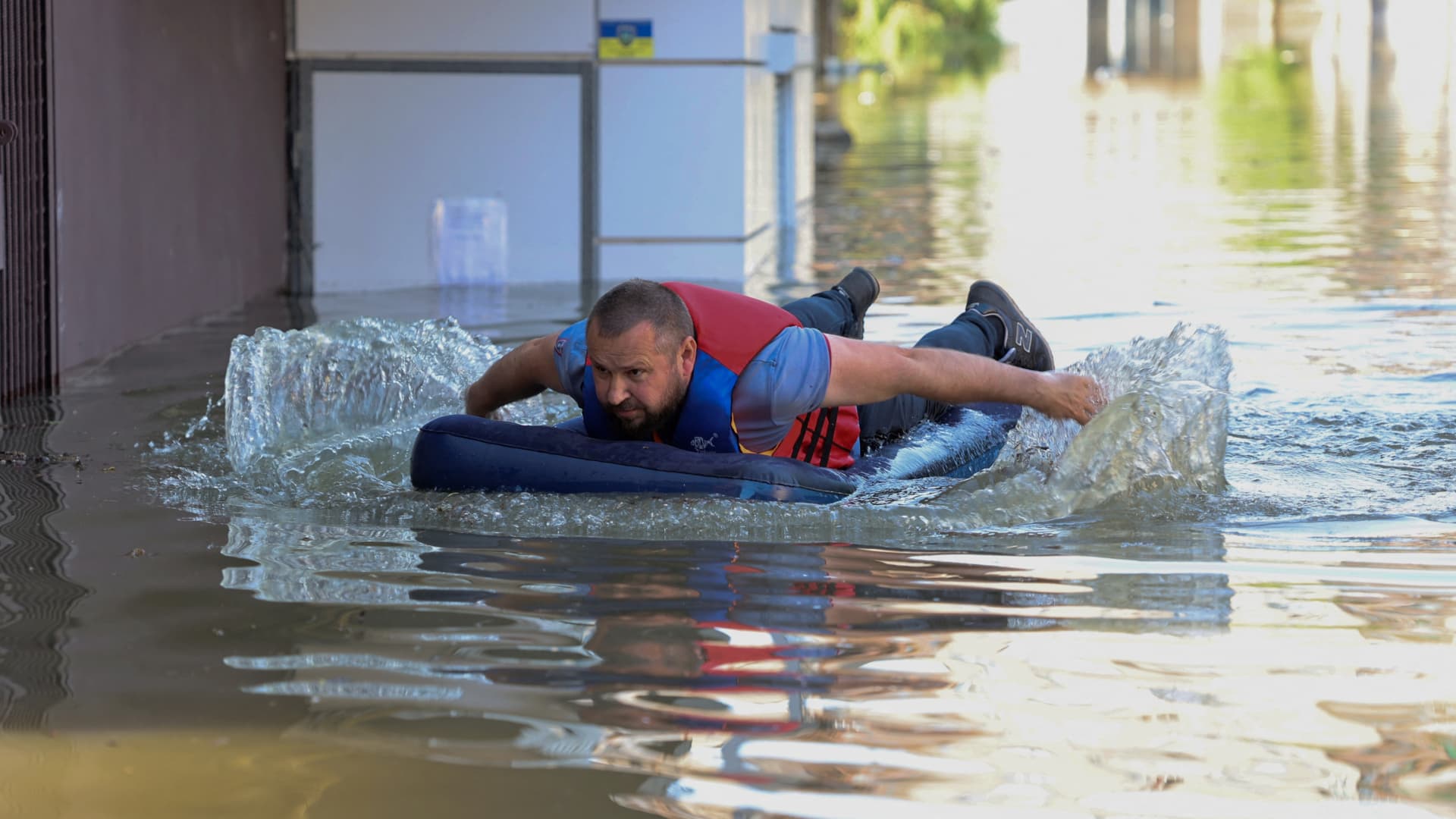 A local resident is seen on an inflatable mattress in a flooded area in Kherson on June 7, 2023, following the destruction of Kakhovka hydroelectric power plant dam.