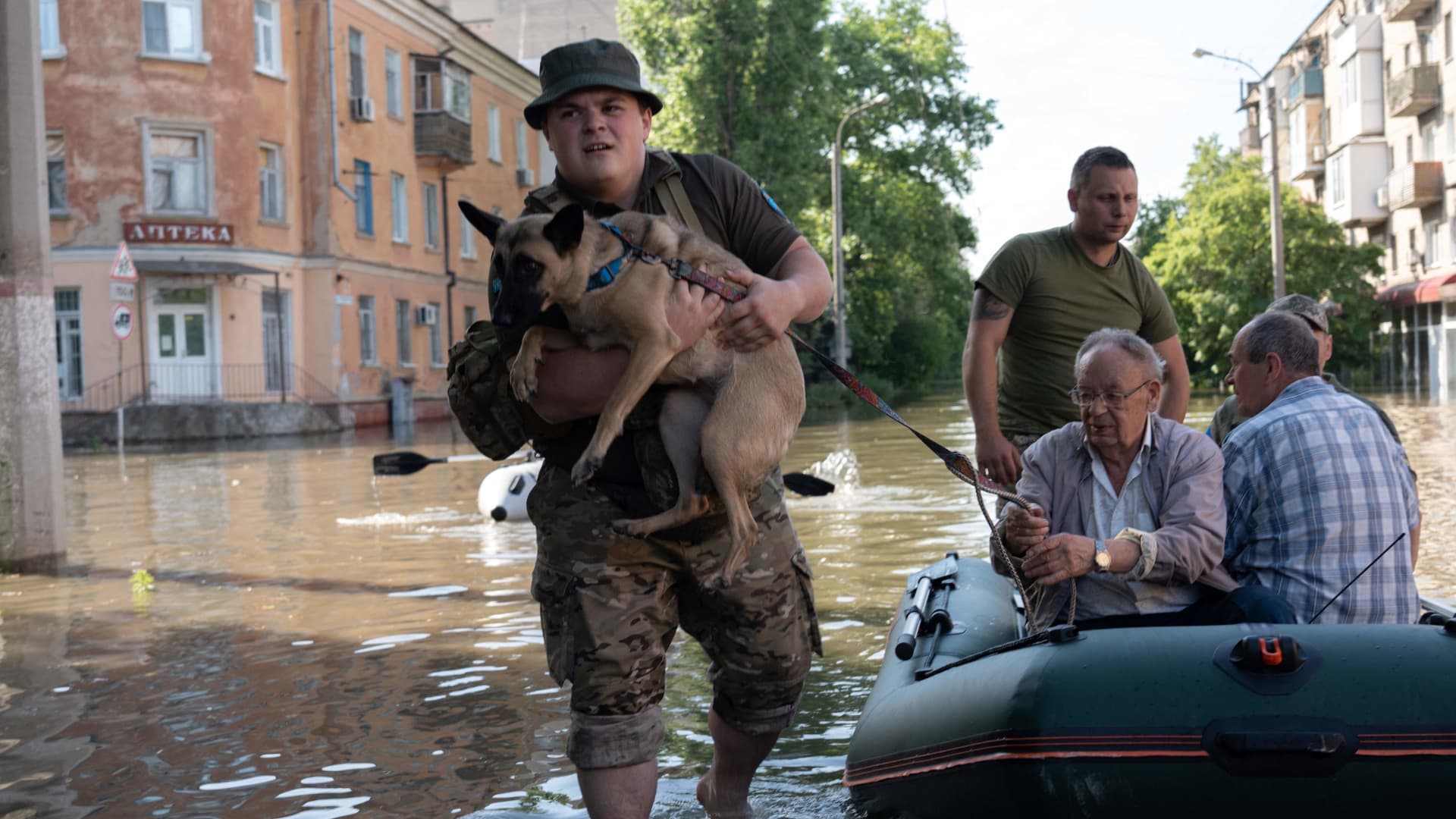 Ukrainian servicemen help local residents during an evacuation from a flooded area in Kherson on June 7, 2023, following damages sustained at the Kakhovka hydroelectric power plant dam. Ukraine was evacuating thousands of people on June 7 after an attack on a major Russian-held dam unleashed a torrent of water, inundating two dozen villages and sparking fears of a humanitarian disaster.