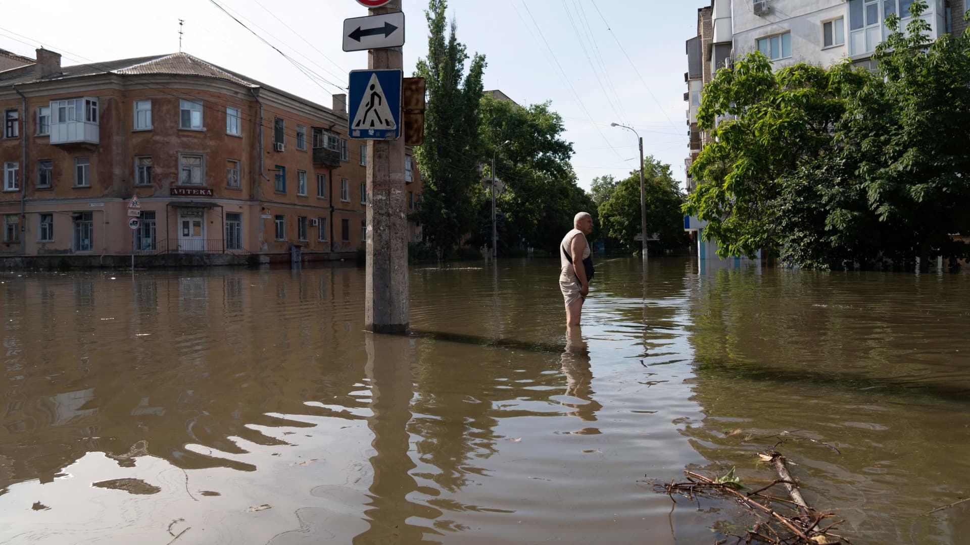 A local resident walks along a flooded street in Kherson on June 7, 2023, following damages sustained at the Kakhovka hydroelectric power plant dam.
