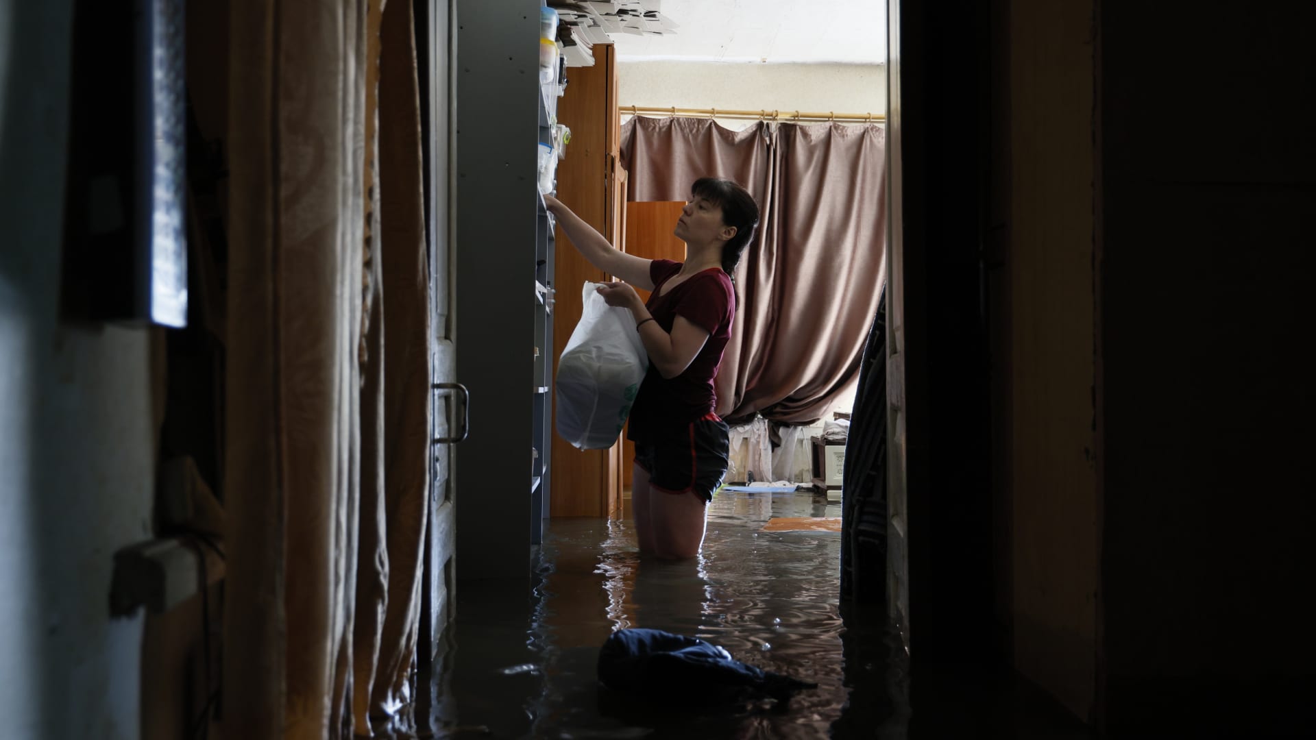 A friend helps a family rescue their belongings from flooding following the destruction of the Kakhovka dam on June 7, 2023 in Kherson, Ukraine.