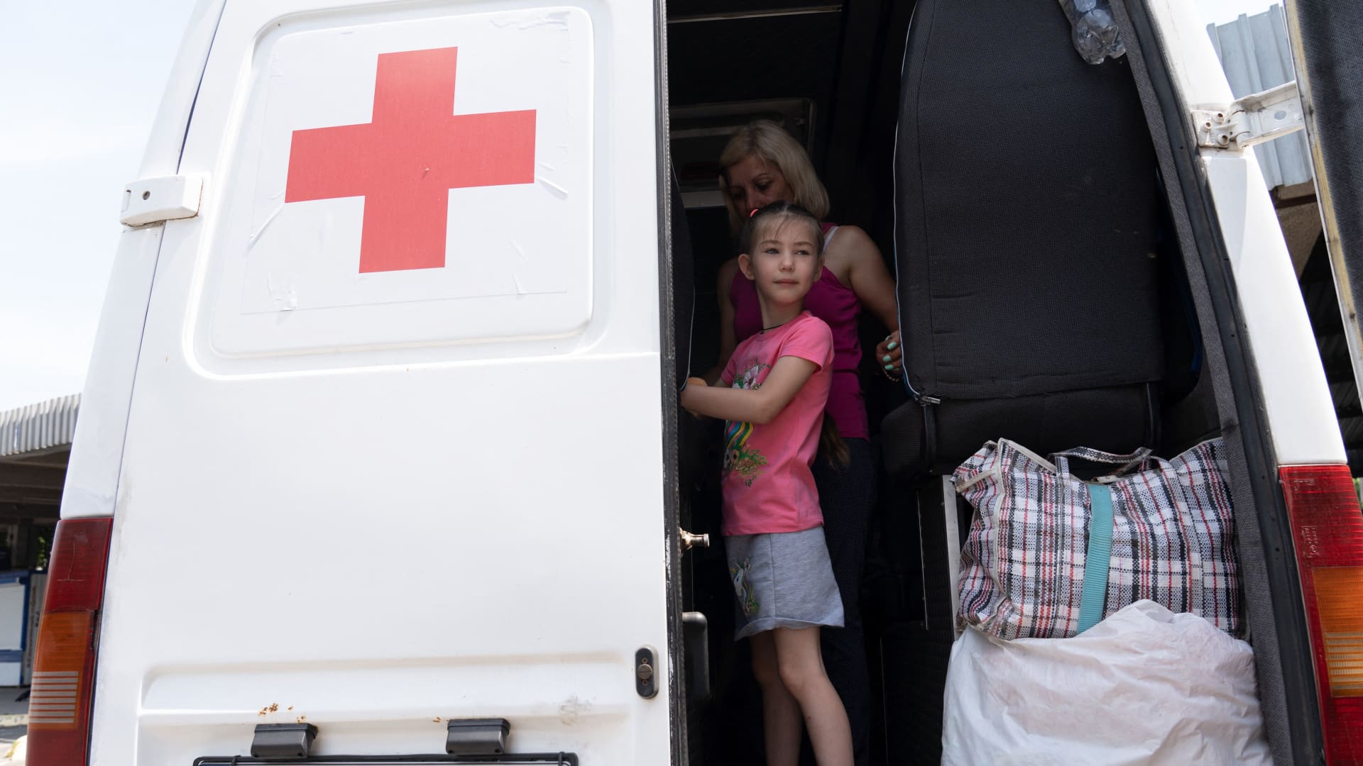 Local residents board an emergency vehicle with their belongings as they evacuate a flooded area in Kherson on June 7, 2023, following damages sustained at Kakhovka hydroelectric power plant dam. 