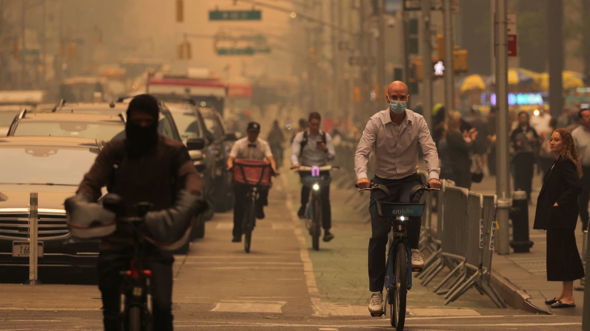 People ride bicycles on 6th Avenue as haze and smoke caused by wildfires in Canada blanket New York City, June 7, 2023.