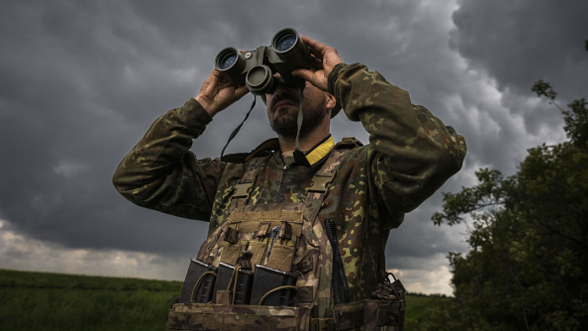 A Ukrainian soldier scouts the area with binoculars on the front line in Donetsk.