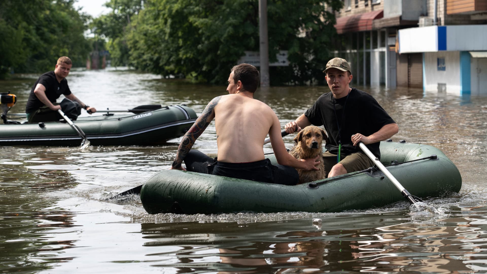 Volunteers carry local residents on inflatable boats during an evacuation from a flooded area in Kherson on June 8, 2023, following damages sustained at Kakhovka hydroelectric power plant dam. Ukrainian President Volodymyr Zelenskyy visited the region flooded by the breached Kakhovka dam on June 8, 2023, as the regional governor said 600 square kilometres were underwater. 